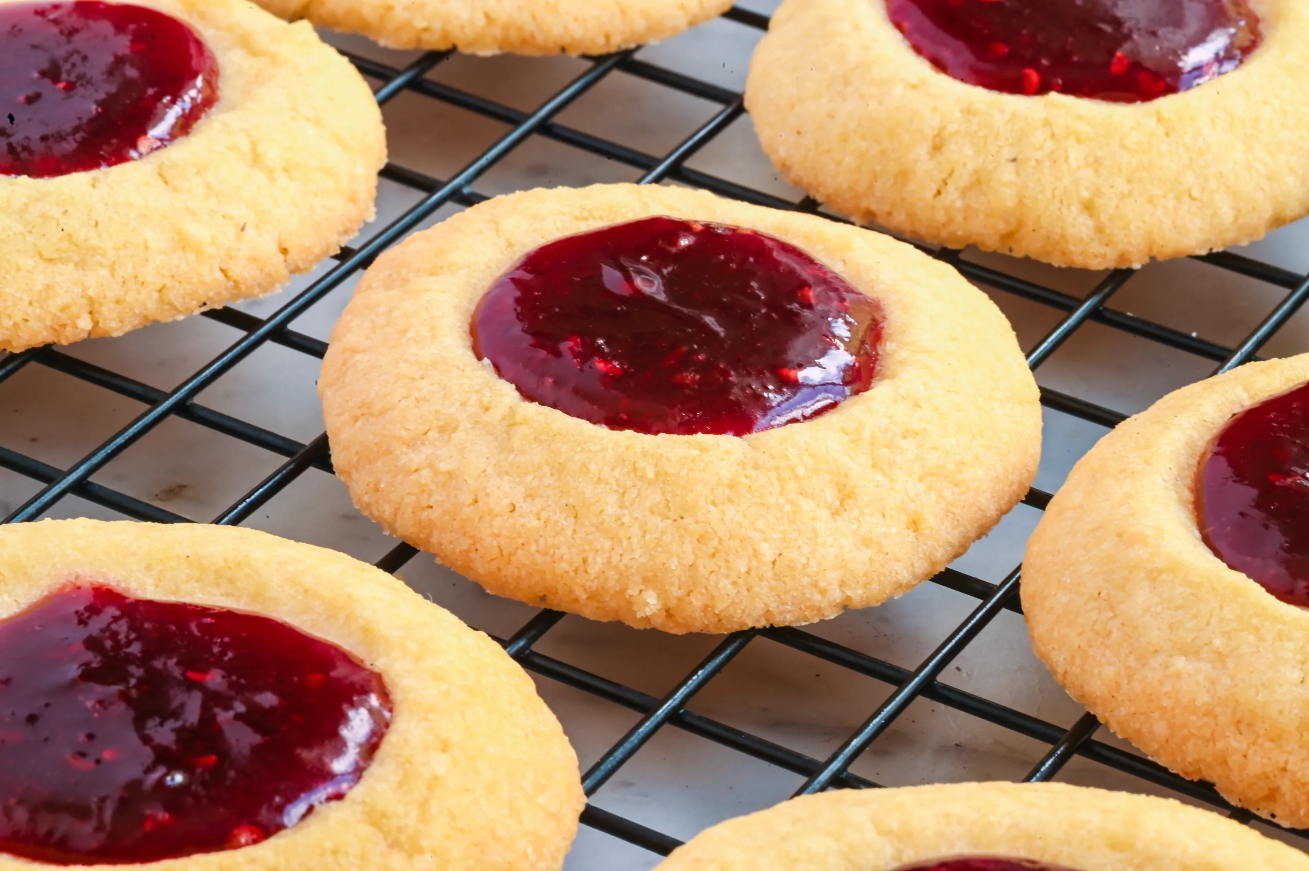 Raspberry thumbprint cookies cooling on a wire rack after baking