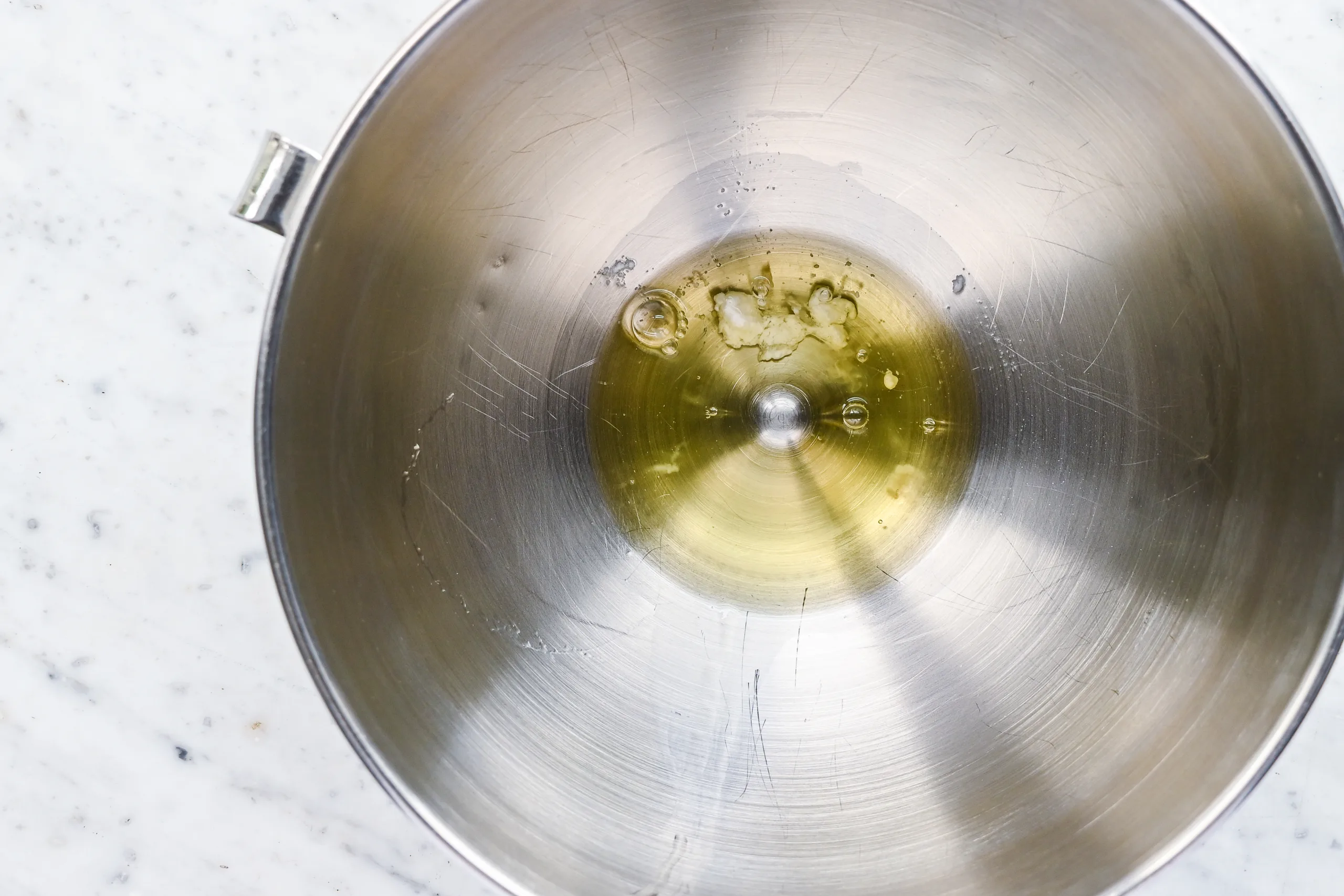 A stand mixer bowl with raw egg whites ready to be whipped for homemade marshmallow fluff.