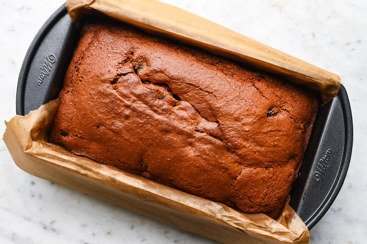 Overhead shot of baked sourdough discard cherry chocolate chip quick bread in a parchment-lined pan.