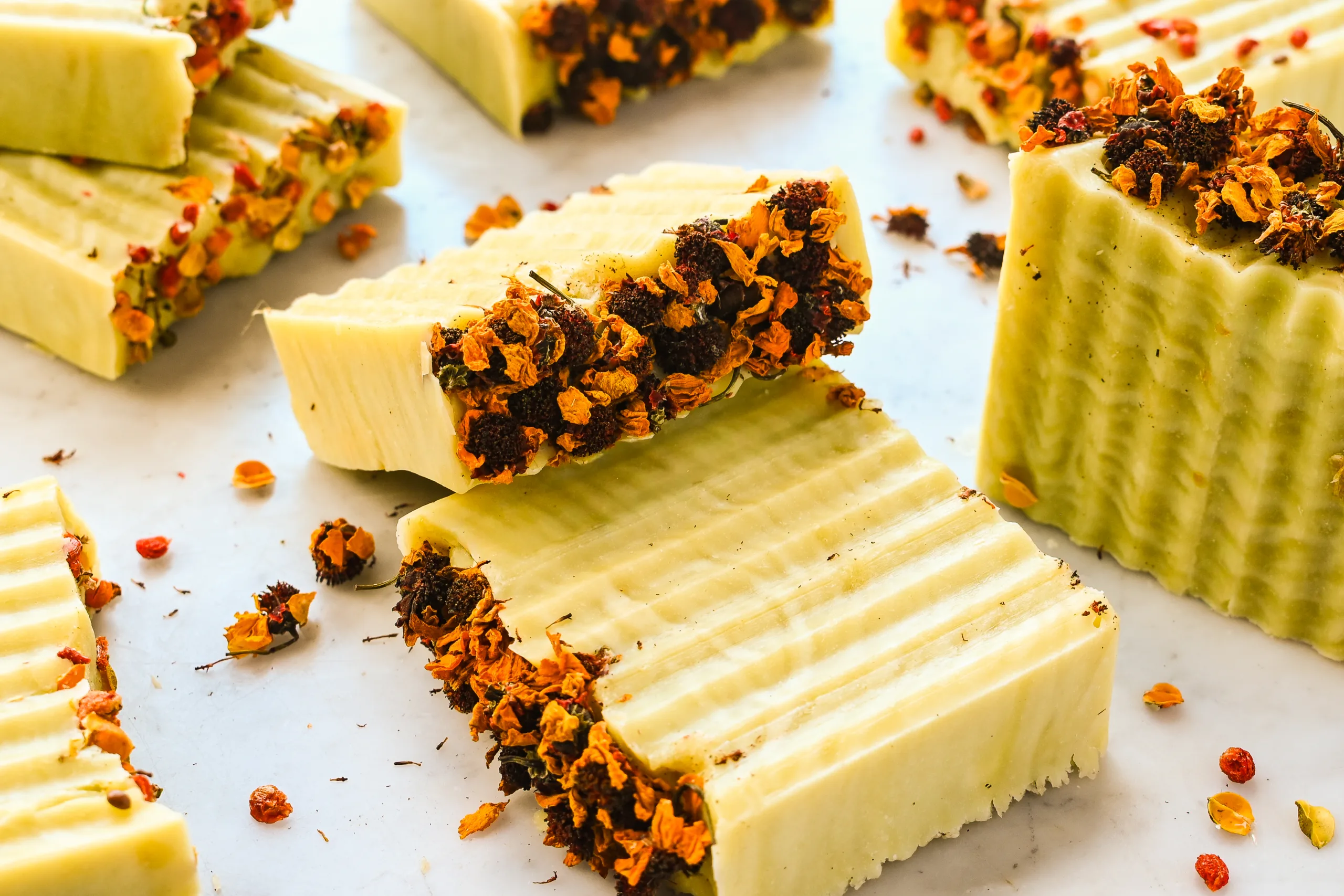 Beautiful finished bars of Bastille soap topped with dried flowers and tied with twine, ready for gifting.