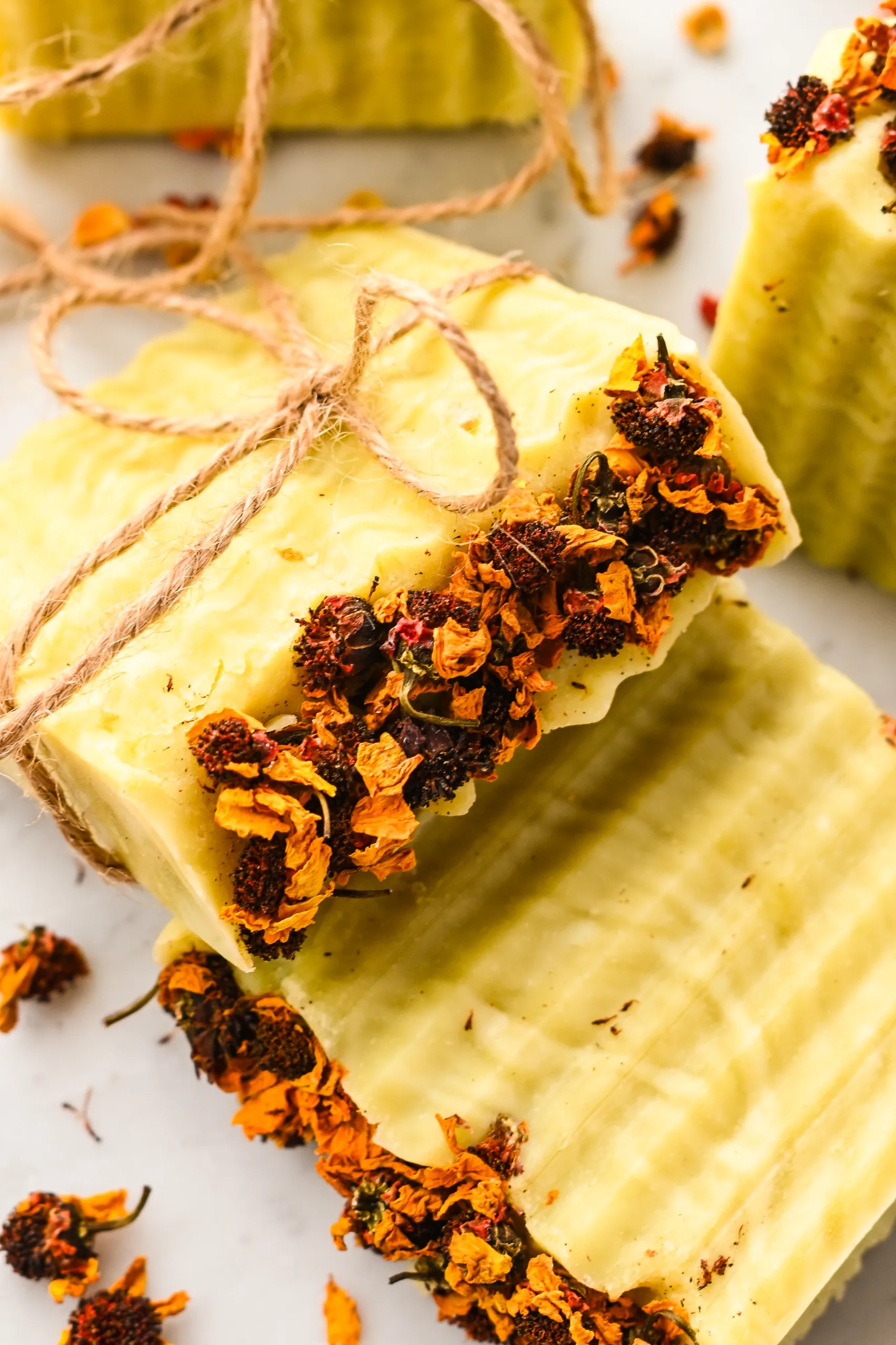 Beautiful finished bars of Bastille soap topped with dried flowers and tied with twine, ready for gifting.