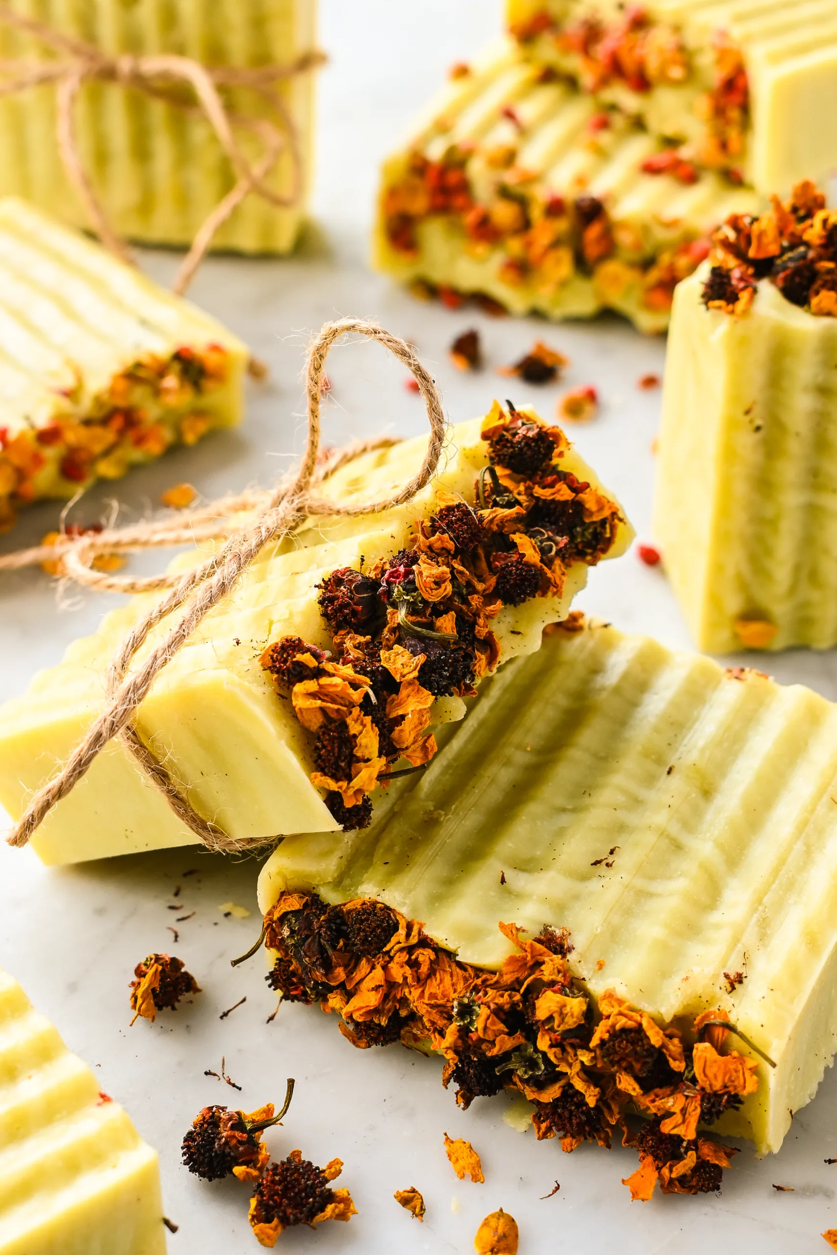Beautiful finished bars of Bastille soap topped with dried flowers and tied with twine, ready for gifting.