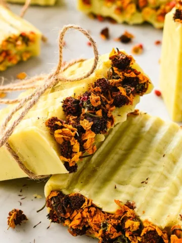 Beautiful finished bars of Bastille soap topped with dried flowers and tied with twine, ready for gifting.