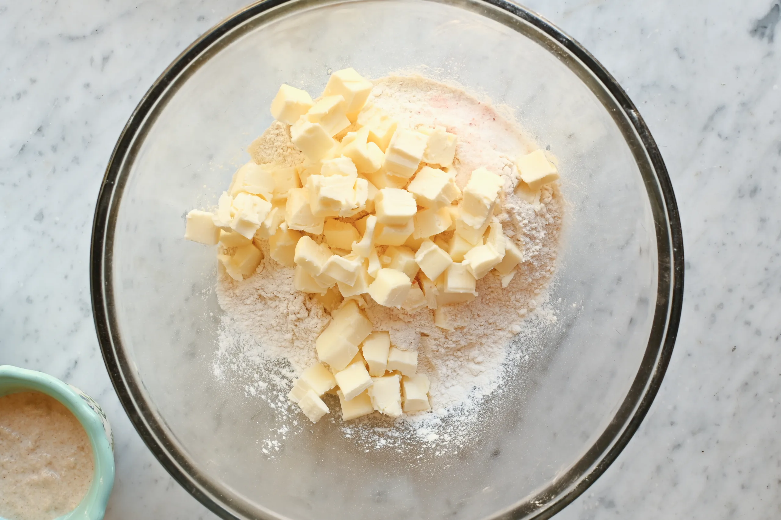 Cubed cold butter added to a bowl of flour mixture for making a flaky sourdough pie crust.