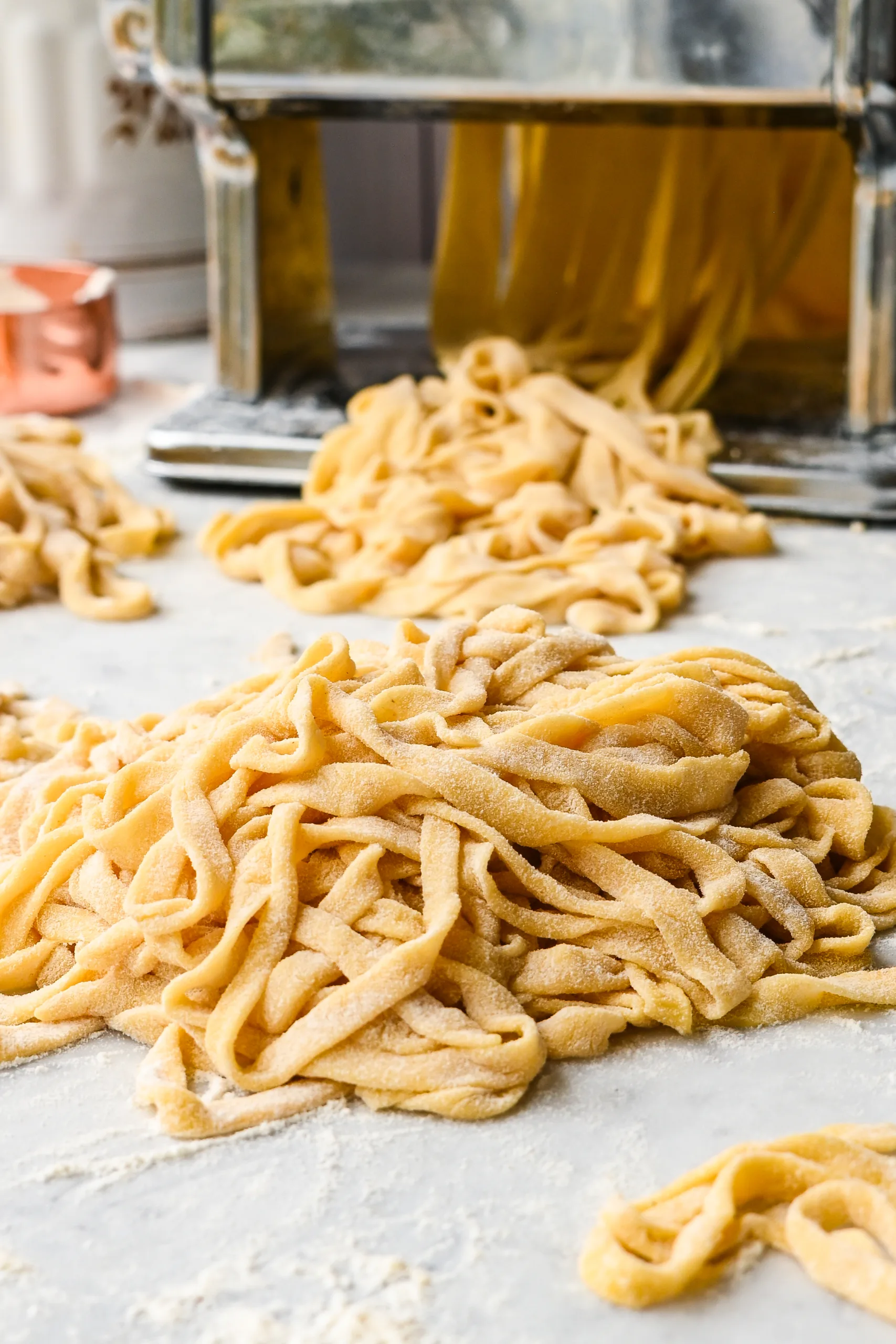 Freshly cut sourdough pasta noodles coated in flour and piled on a work surface, ready for drying or cooking.