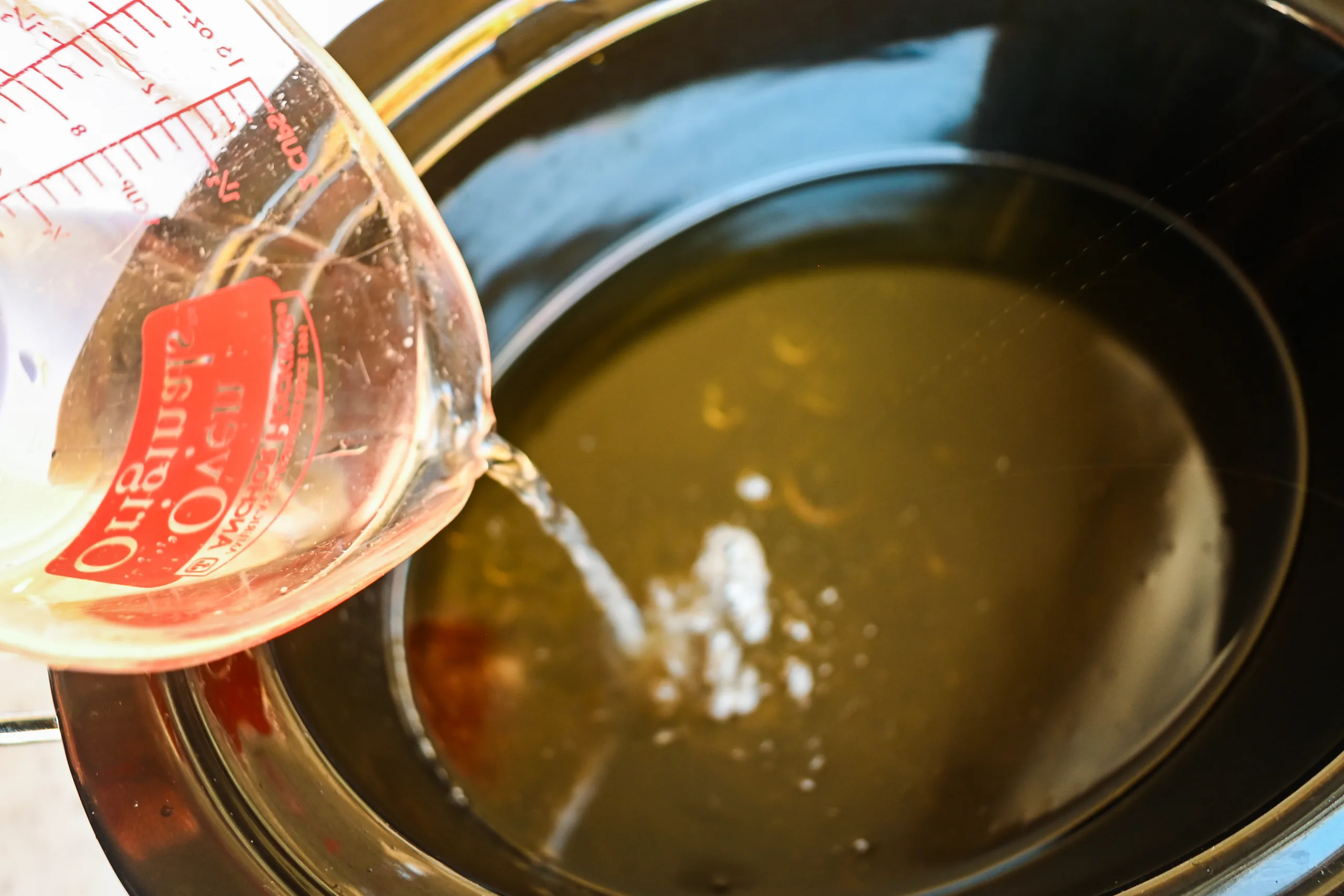 Pouring hot water into melted tallow in a slow cooker for the salt-wash purification process.