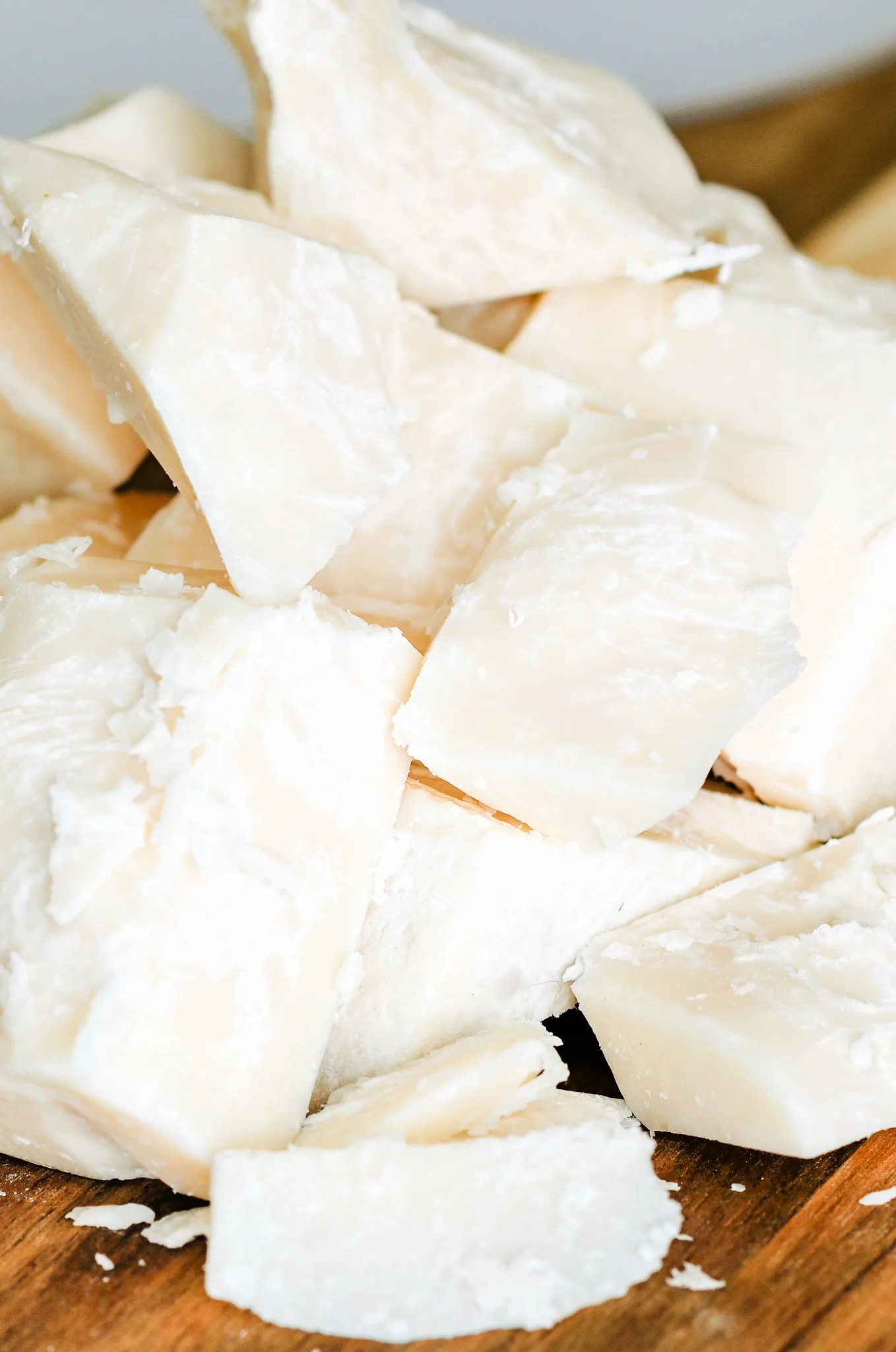 Chunks of solid beef tallow on a wooden cutting board, ready to be purified for skincare use.