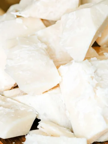 Close-up of creamy white chunks of beef tallow on a wooden board, showcasing the natural texture before purification for skincare use.