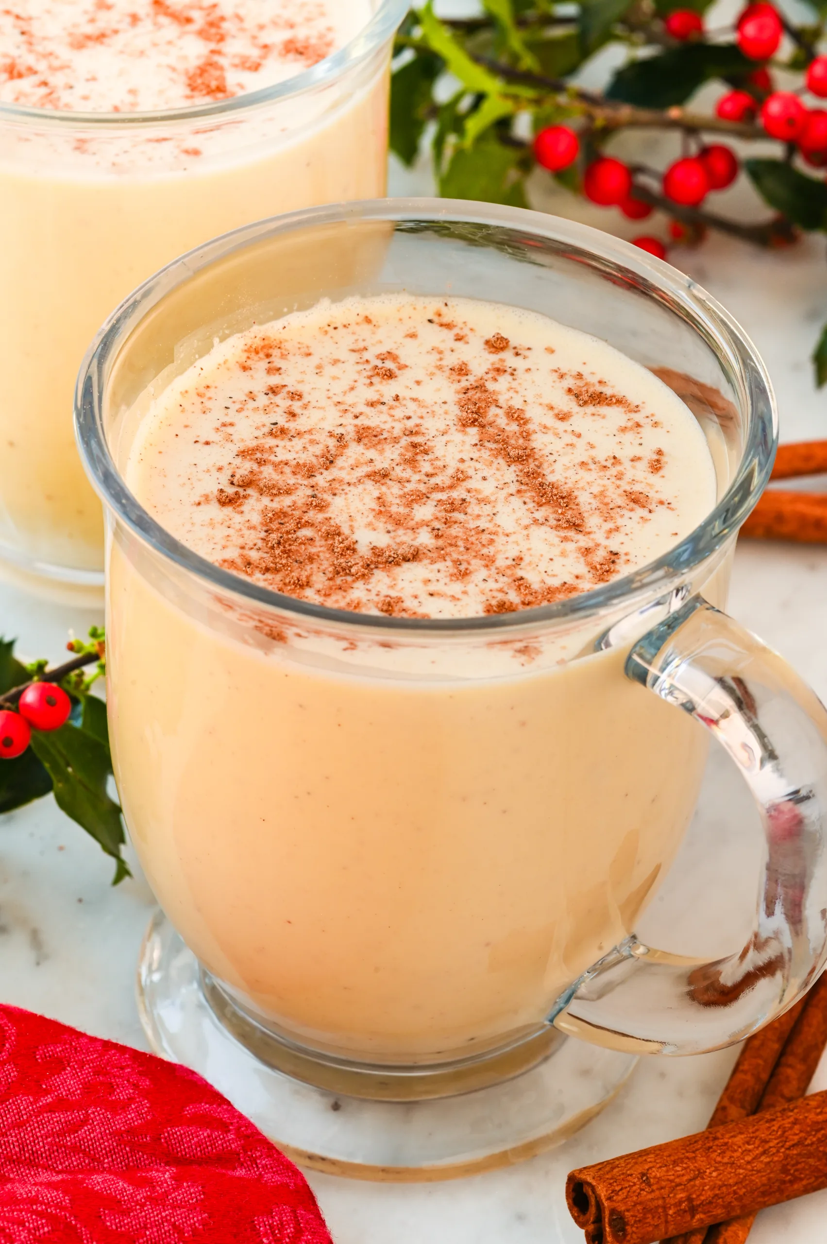 Homemade eggnog in a clear glass with a sprinkle of nutmeg on top.