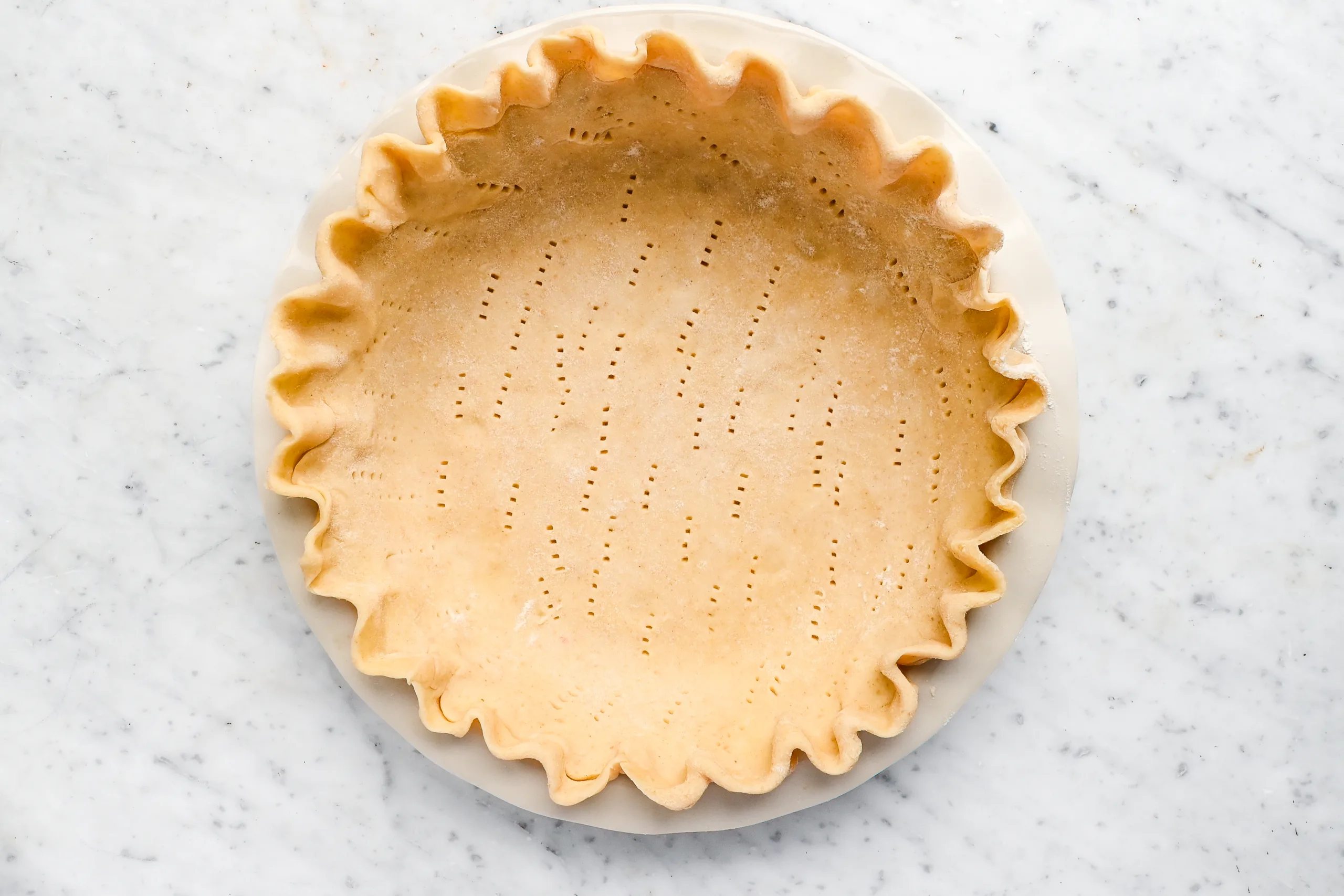Unbaked pie crust with crimped edges and fork holes, ready for Pennsylvania Dutch Funny Cake.