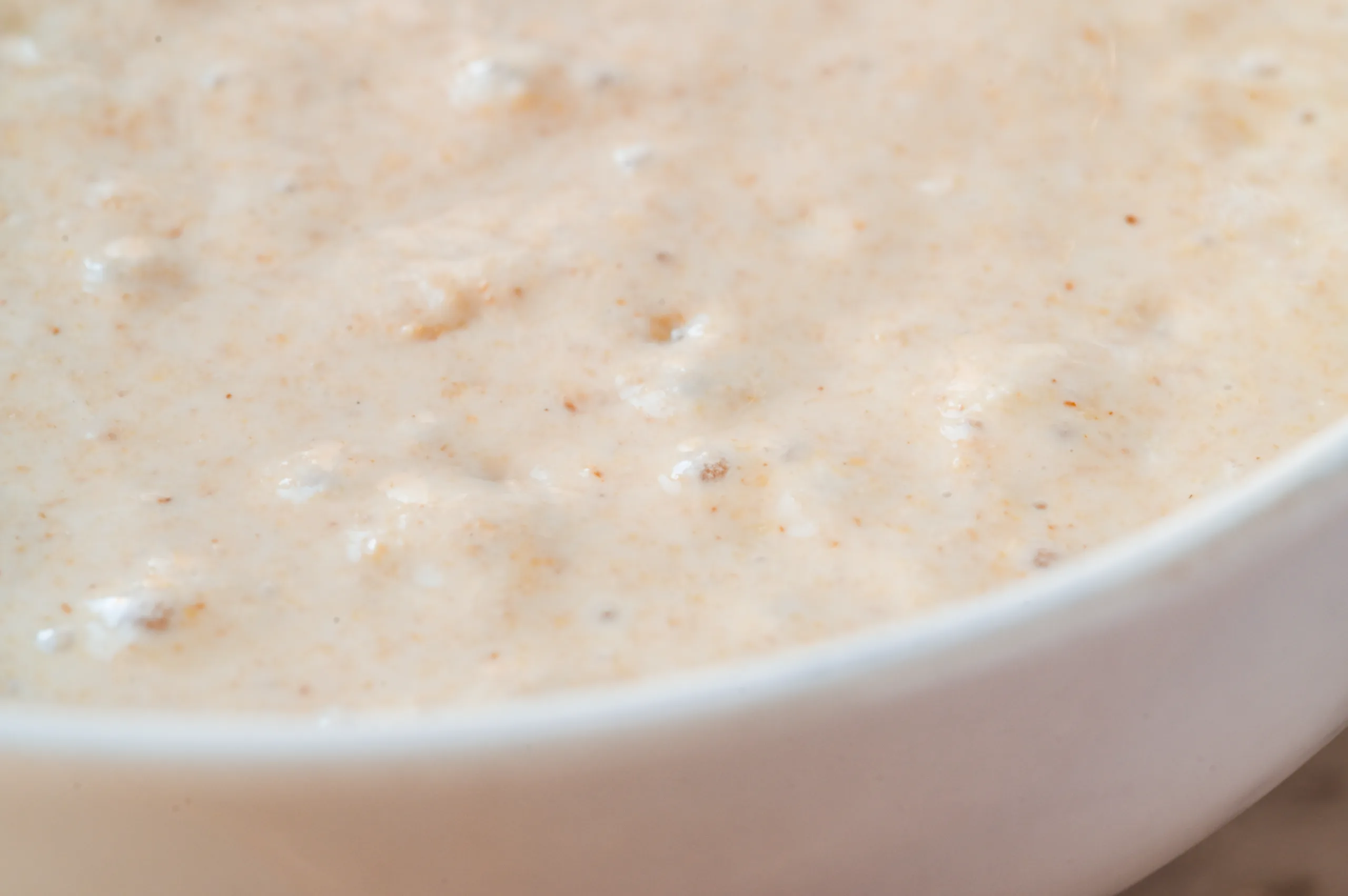 Bubbly sourdough discard in a white bowl showing signs of fermentation.