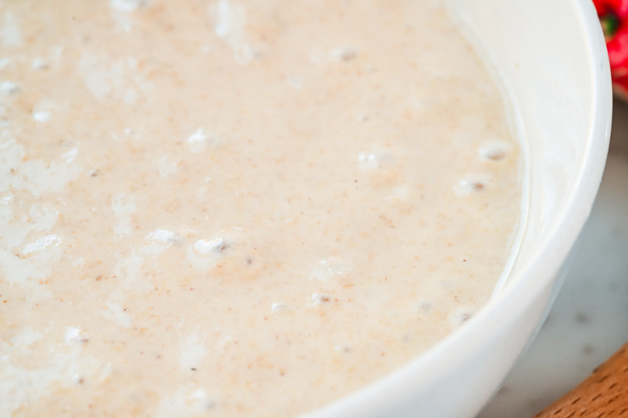 Close-up of bubbly sourdough discard in a white bowl, showing its creamy texture and natural fermentation bubbles, ready to use in baking or recipes.