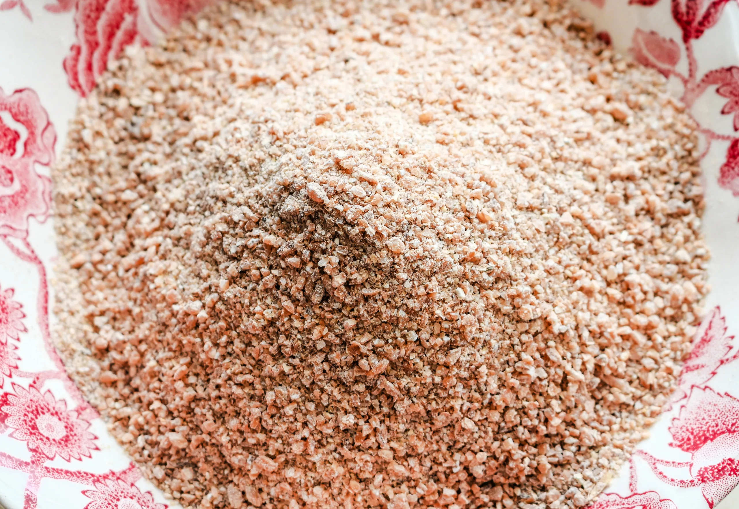 Freshly milled whole wheat flour in a patterned bowl, showing the coarse texture of home-milled grains.
