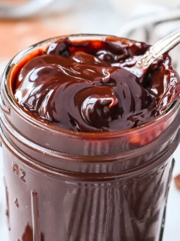 Rich homemade fudge sauce in a jar, thick and shiny from real melted chocolate and cocoa powder.