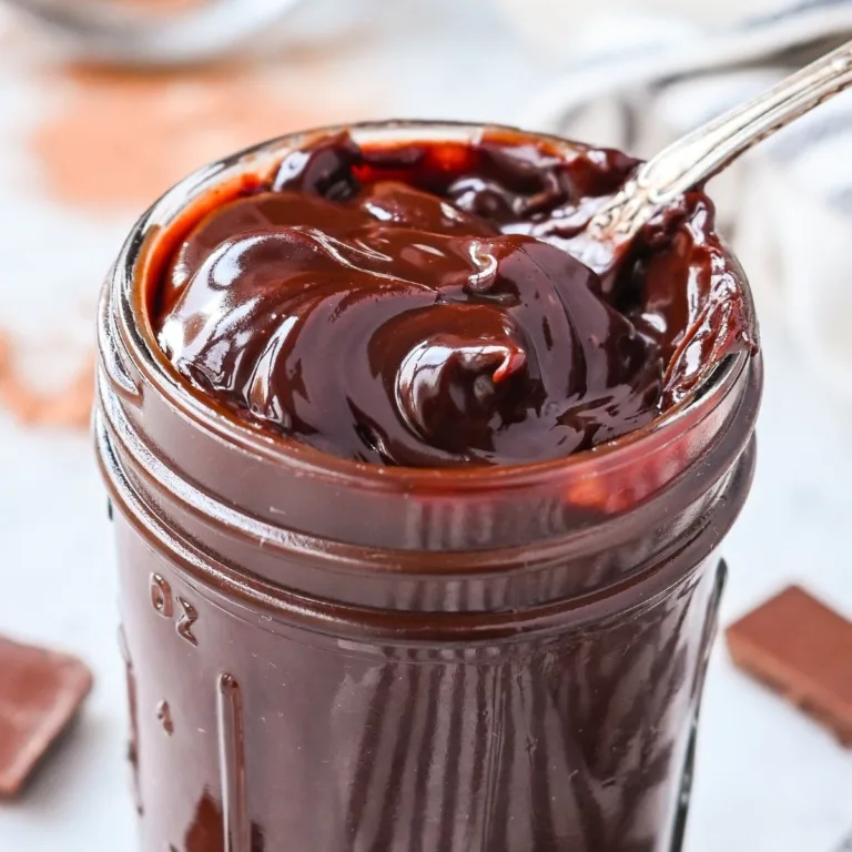 Rich homemade fudge sauce in a jar, thick and shiny from real melted chocolate and cocoa powder.