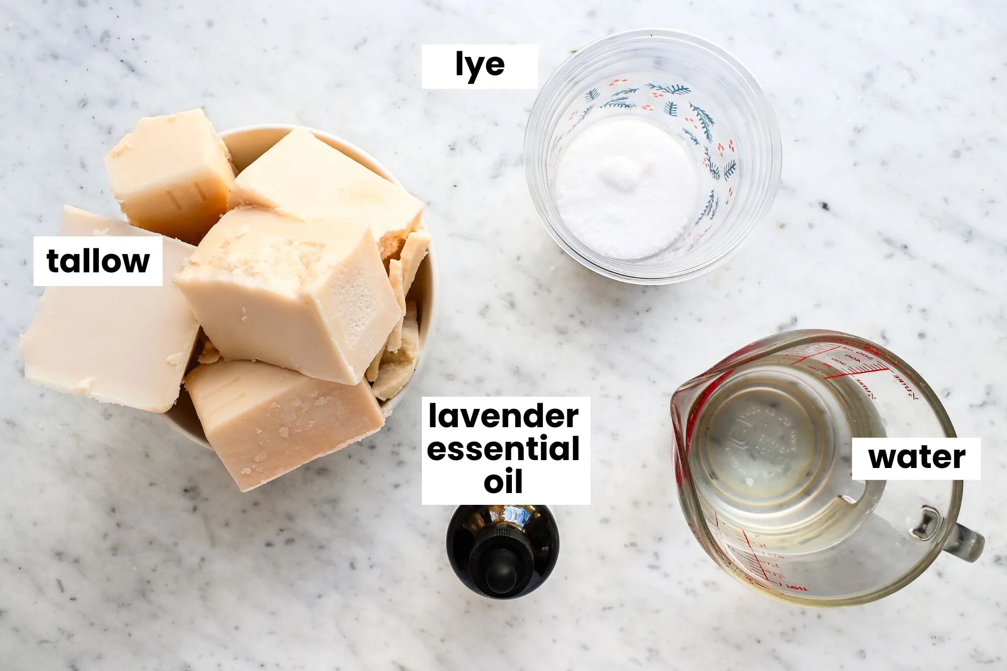 Cubes of rendered beef tallow, lye, distilled water, and lavender essential oil measured out for homemade tallow soap bars.
