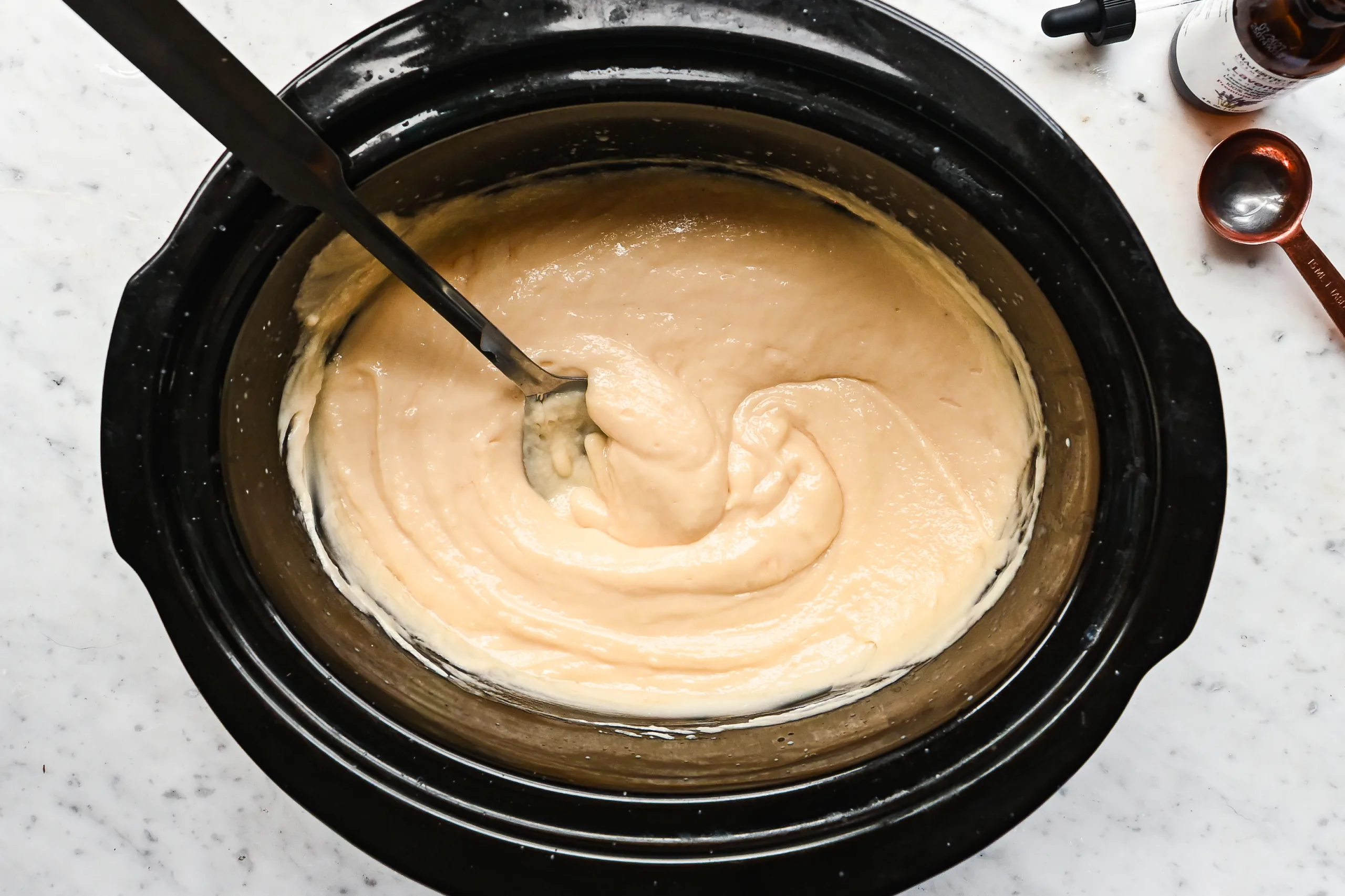 Creamy tallow soap mixture thickening in slow cooker before pouring into mold.