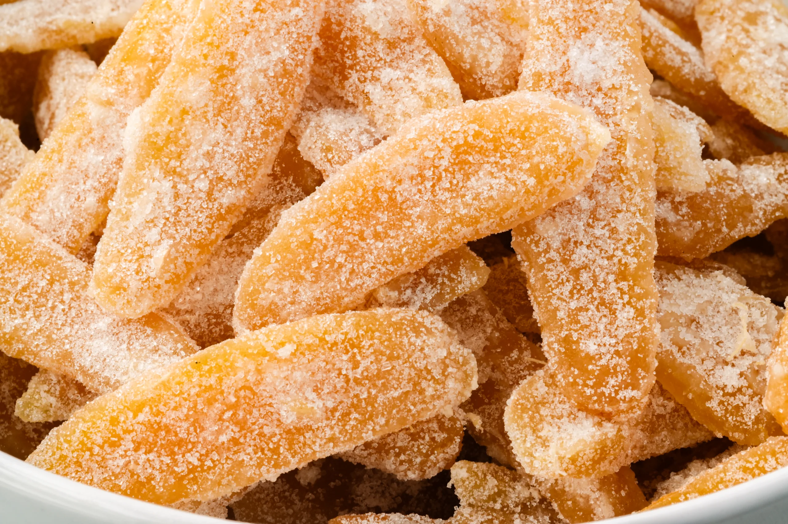 A detailed close-up showing the sugary coating on homemade candied ginger slices.