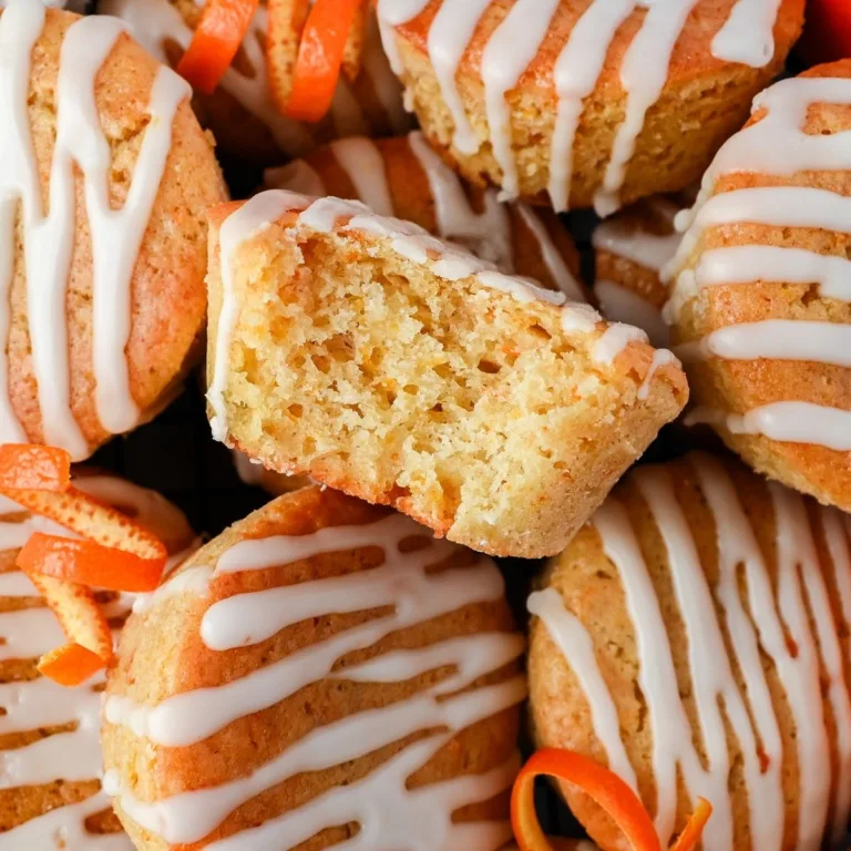 Halved sourdough discard orange muffin resting on glazed muffins below, showing the soft, tender crumb and bright orange zest throughout.