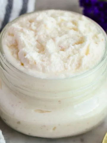Close-up of DIY foot scrub with tallow in a glass jar, showing a fluffy whipped texture and creamy natural sugar scrub consistency.