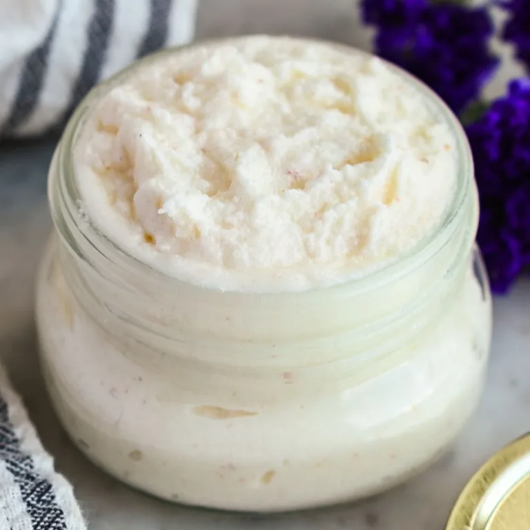 Close-up of DIY foot scrub with tallow in a glass jar, showing a fluffy whipped texture and creamy natural sugar scrub consistency.