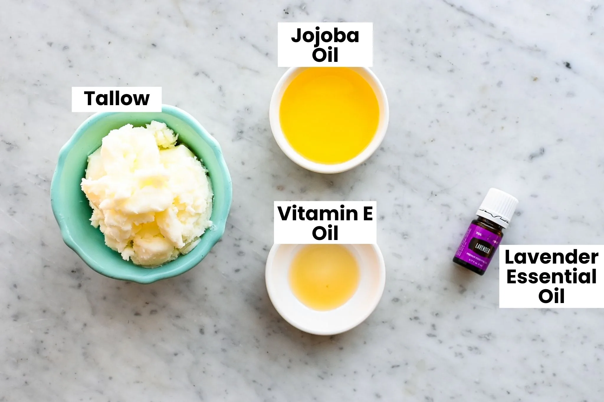 Overhead shot of natural skincare ingredients for tallow face cream, including rendered tallow, oils, and lavender essential oil.