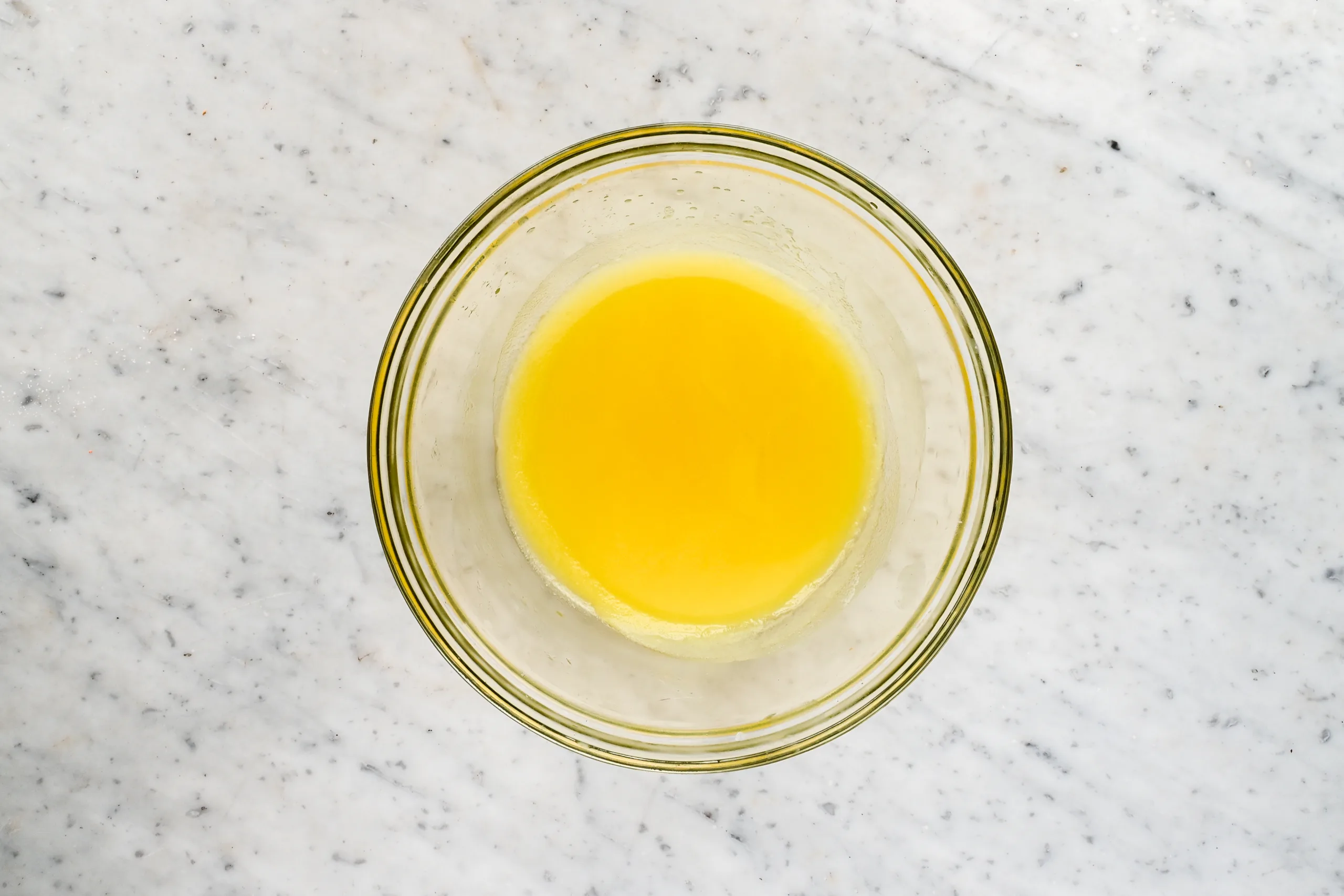 Melted grass fed beef tallow fully liquefied in a glass bowl during the face cream making process.