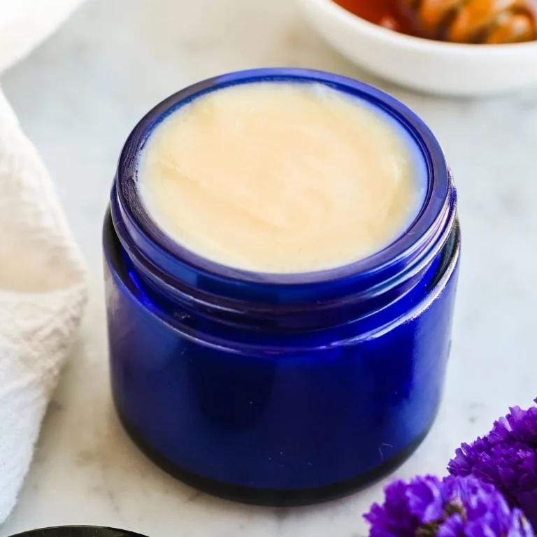 Finished homemade tallow and honey balm in a blue glass jar showing a smooth, creamy surface after setting.