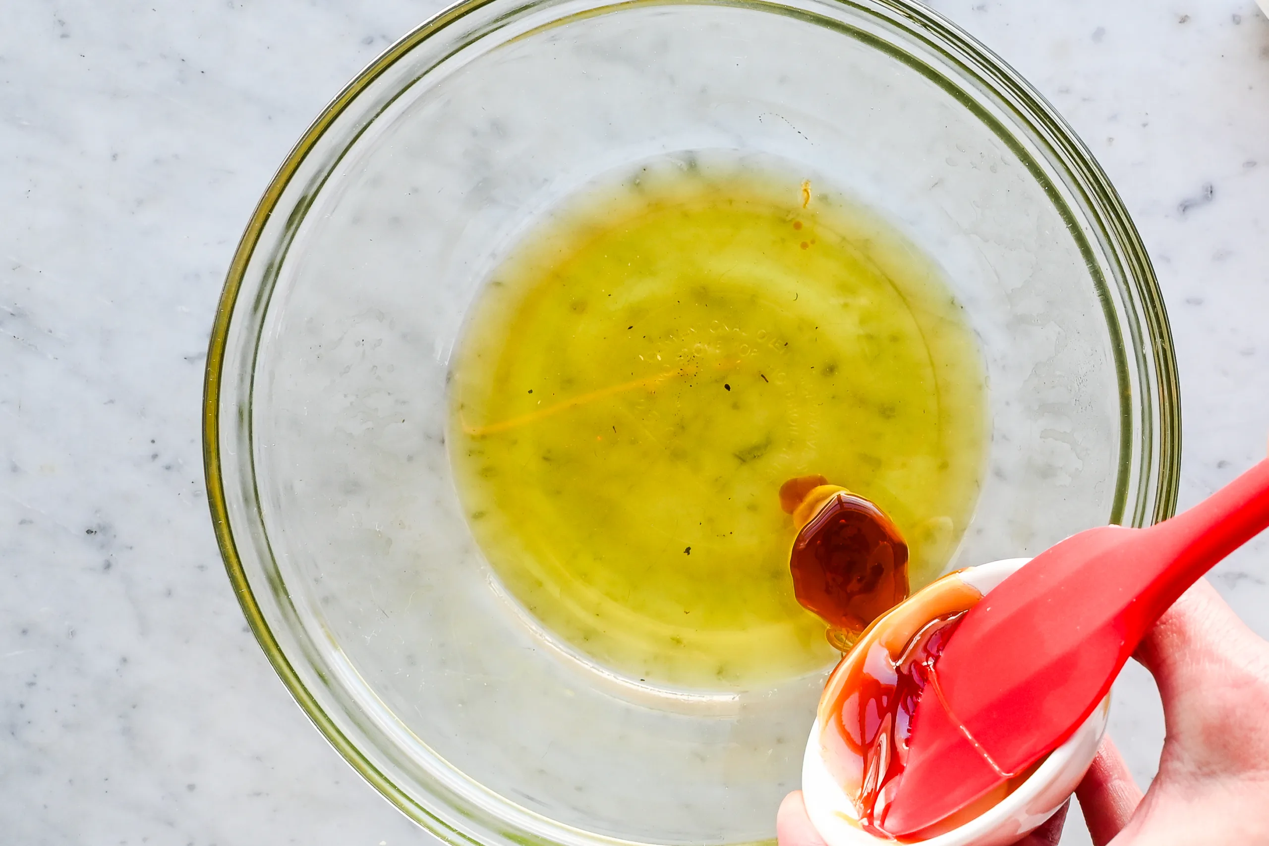 Raw honey being poured into melted tallow and oil mixture while making old-fashioned tallow honey balm.