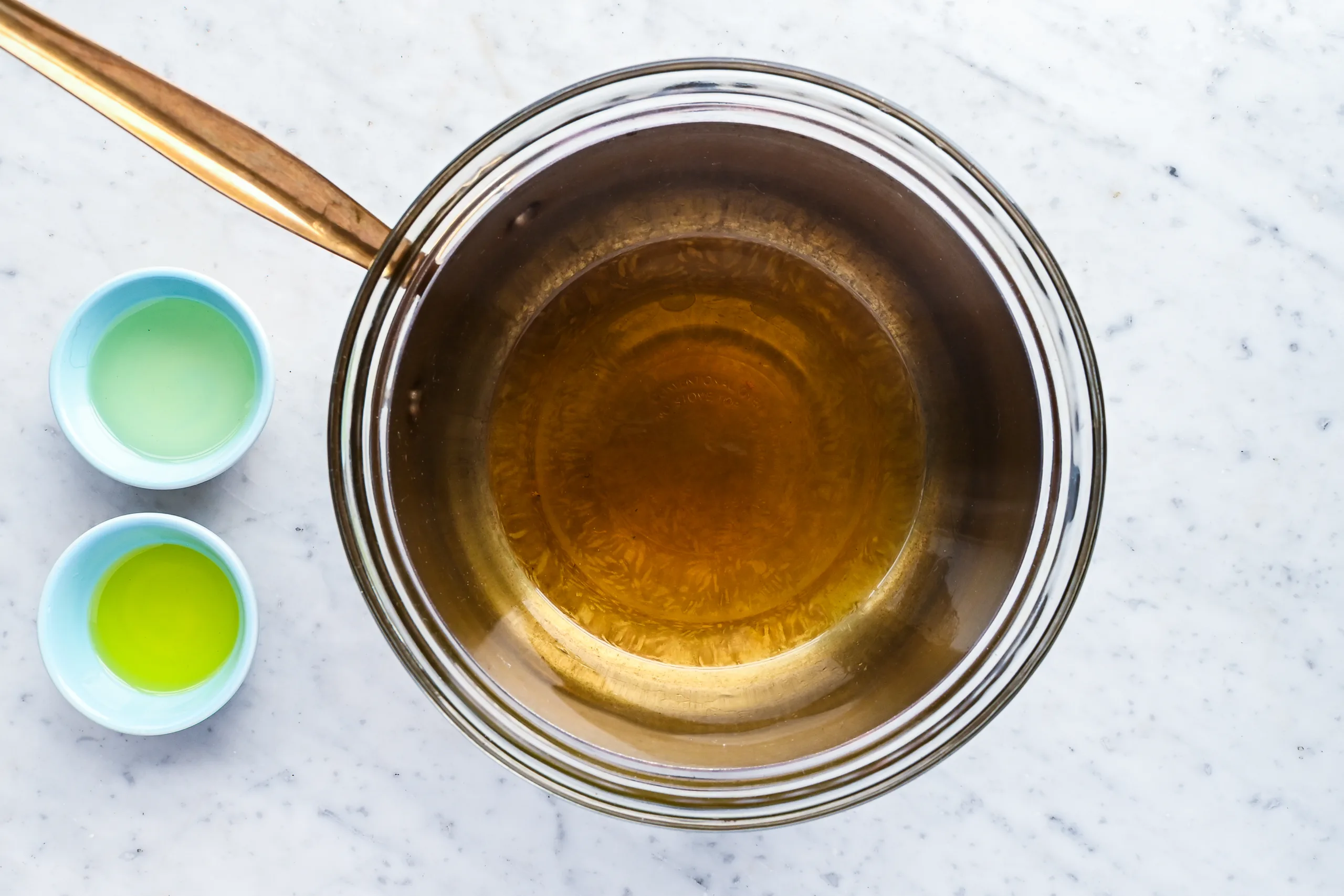 Melted beeswax and tallow mixture in a bowl during the process of making homemade hair pomade.
