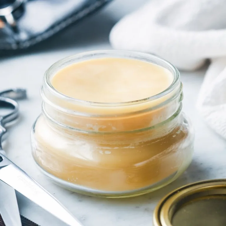Side view of homemade natural pomade made with beeswax and tallow set in a small glass jar for men’s hair styling.