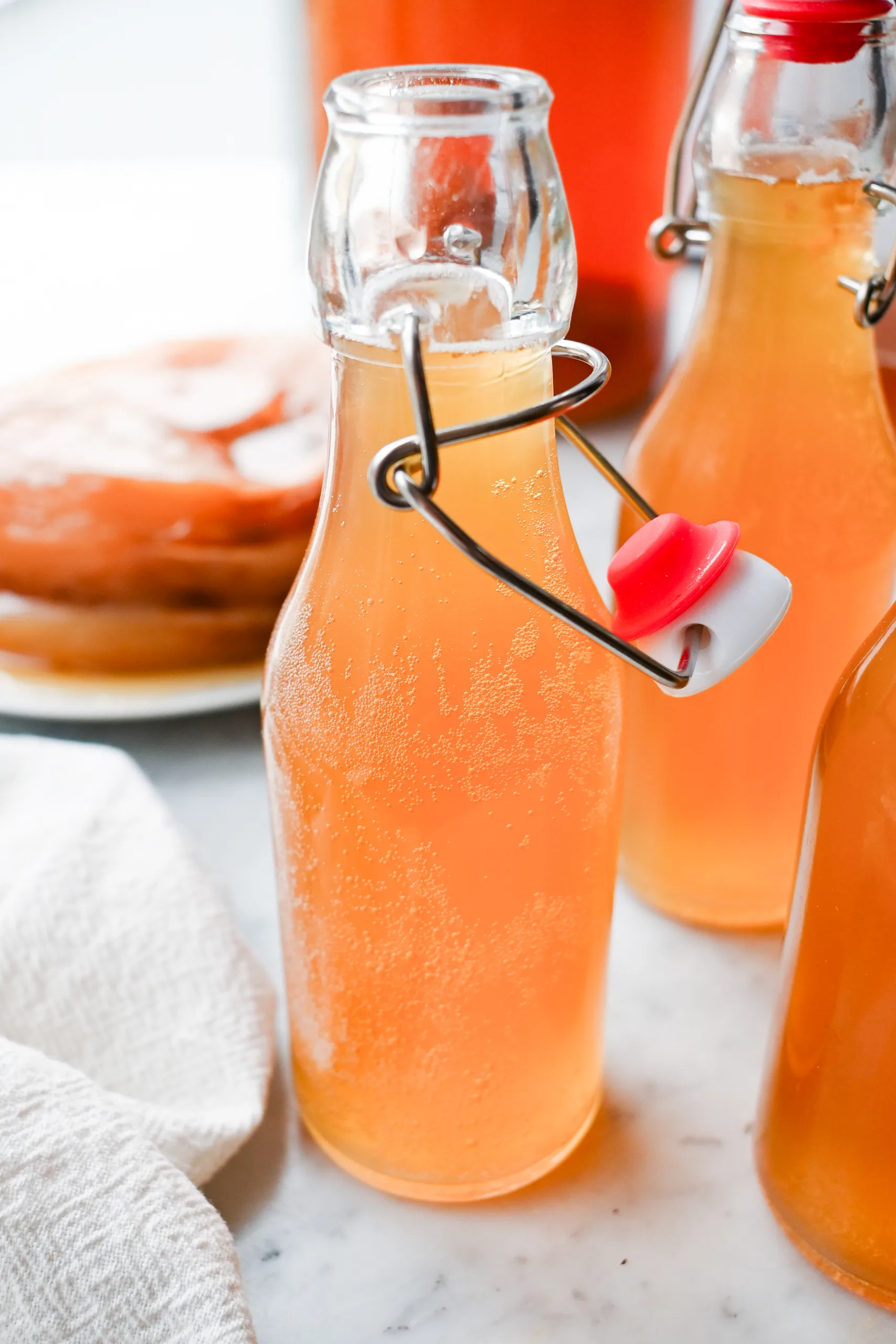 Sparkling homemade kombucha in glass bottles on a kitchen counter after second fermentation.
