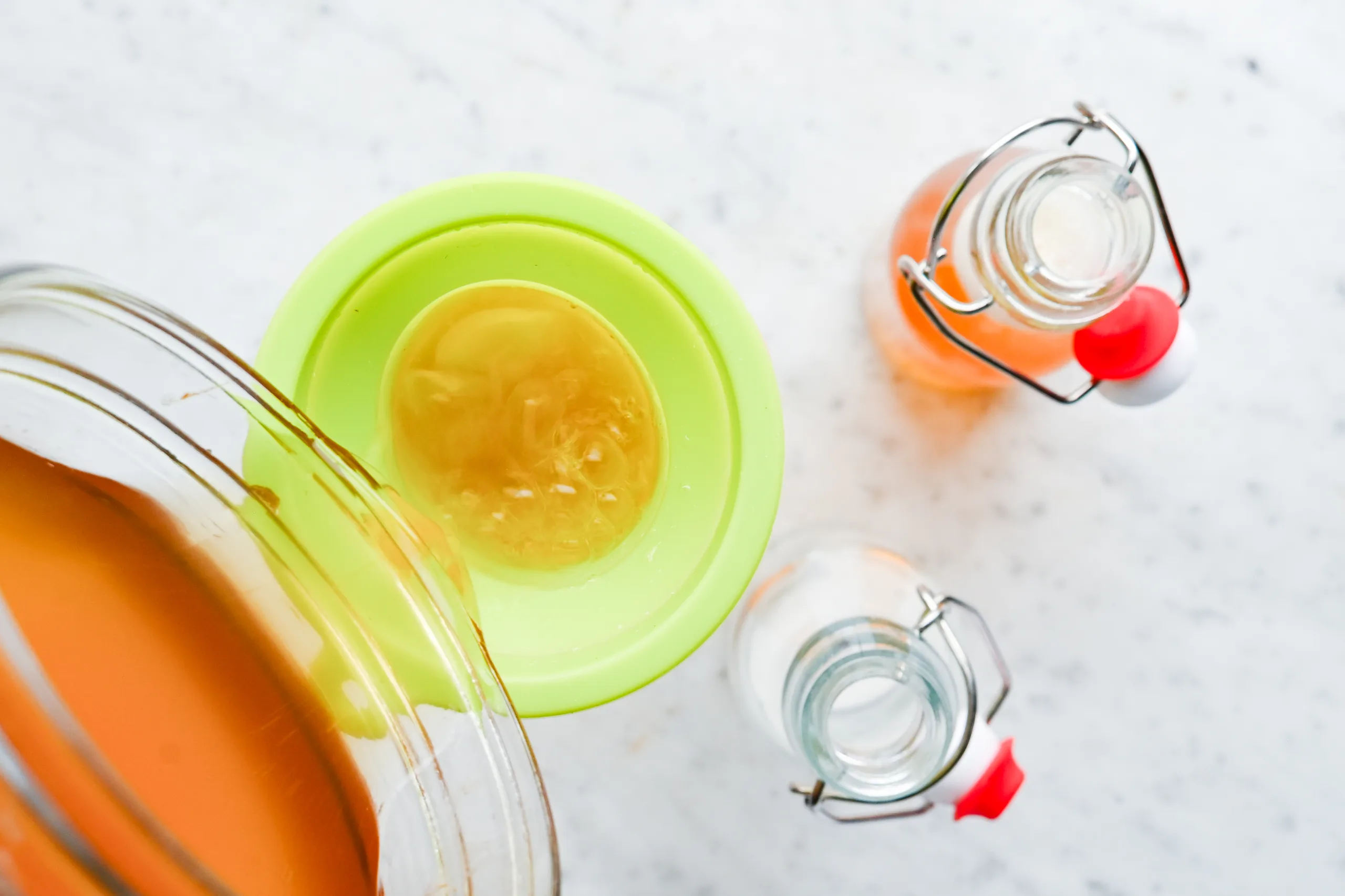 Homemade kombucha with swing-top bottles and a funnel prepared for the second fermentation.
