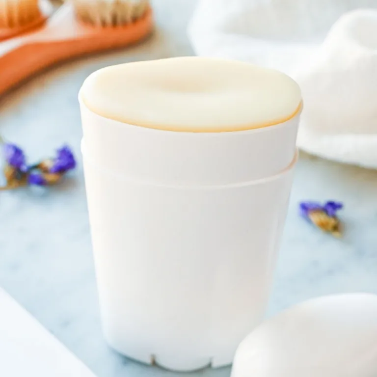 Close-up of homemade natural tallow deodorant in a reusable white deodorant container on a marble countertop.