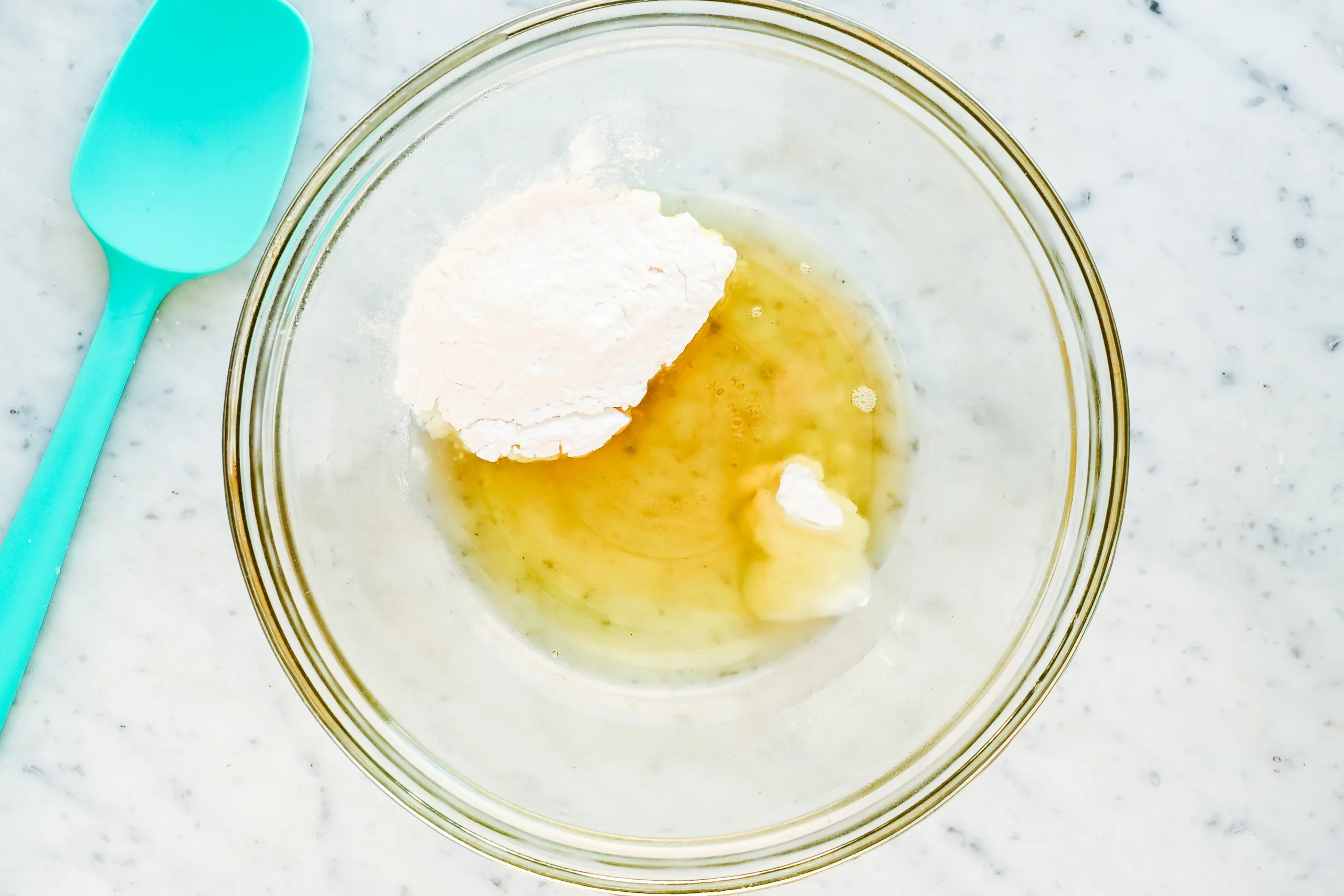 Arrowroot powder and melted oils in a glass bowl for making homemade natural tallow deodorant.