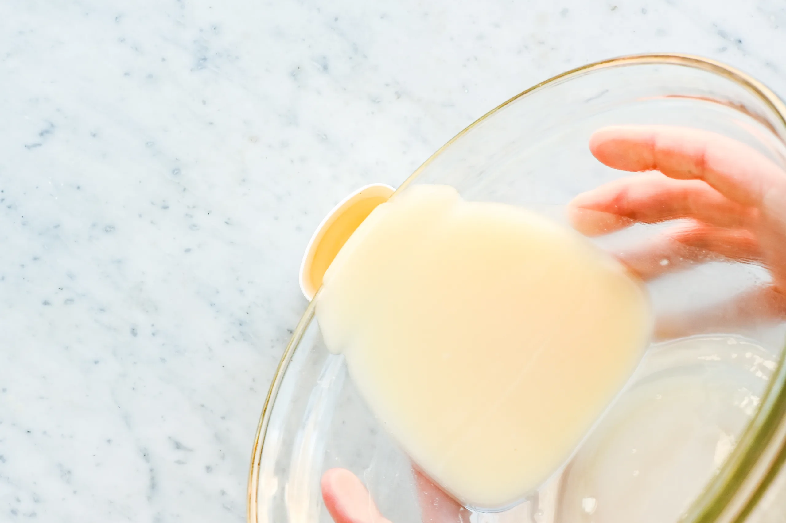 Pouring melted tallow deodorant mixture into an empty reusable deodorant tube.