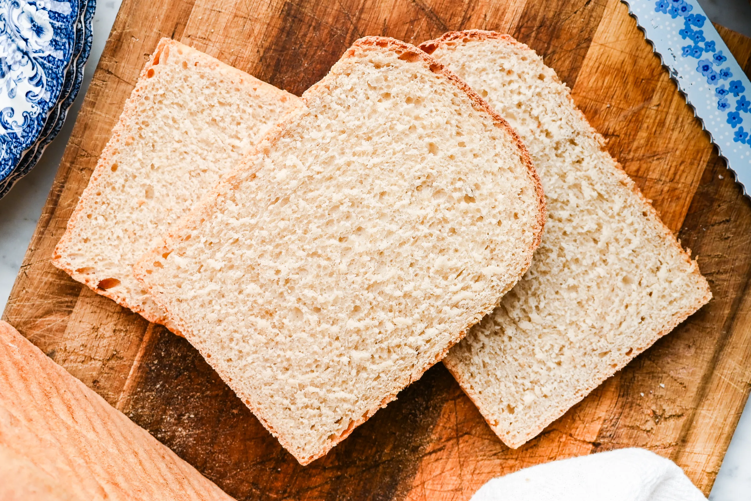 Three slices of soft sourdough discard sandwich bread arranged on a wooden cutting board.