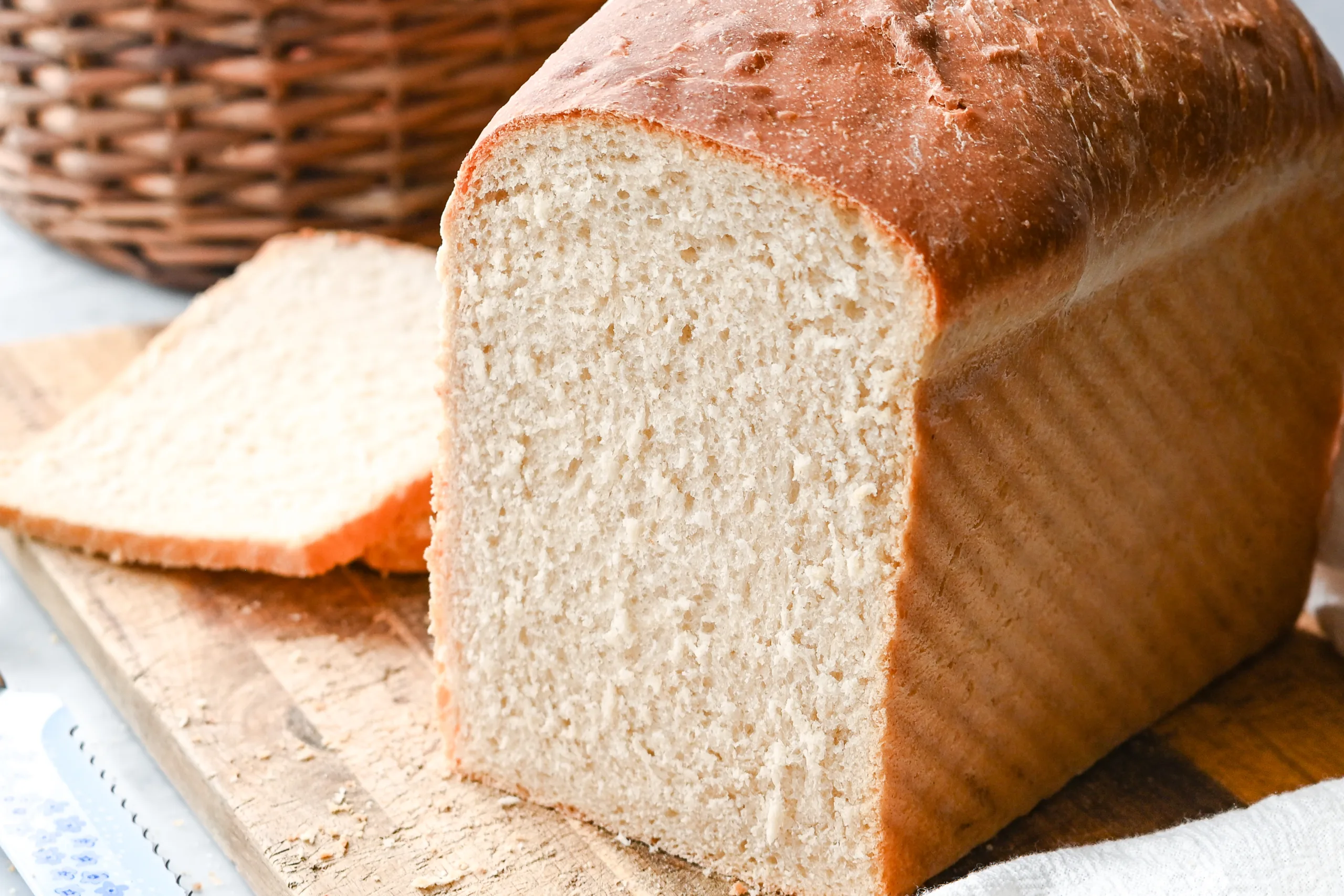 Freshly baked sourdough discard sandwich bread loaf with a golden brown crust sitting on a wooden cutting board.