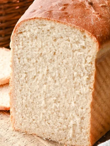 Close-up of sliced sourdough discard sandwich bread showing a soft, fluffy crumb and golden brown crust on a wooden cutting board.