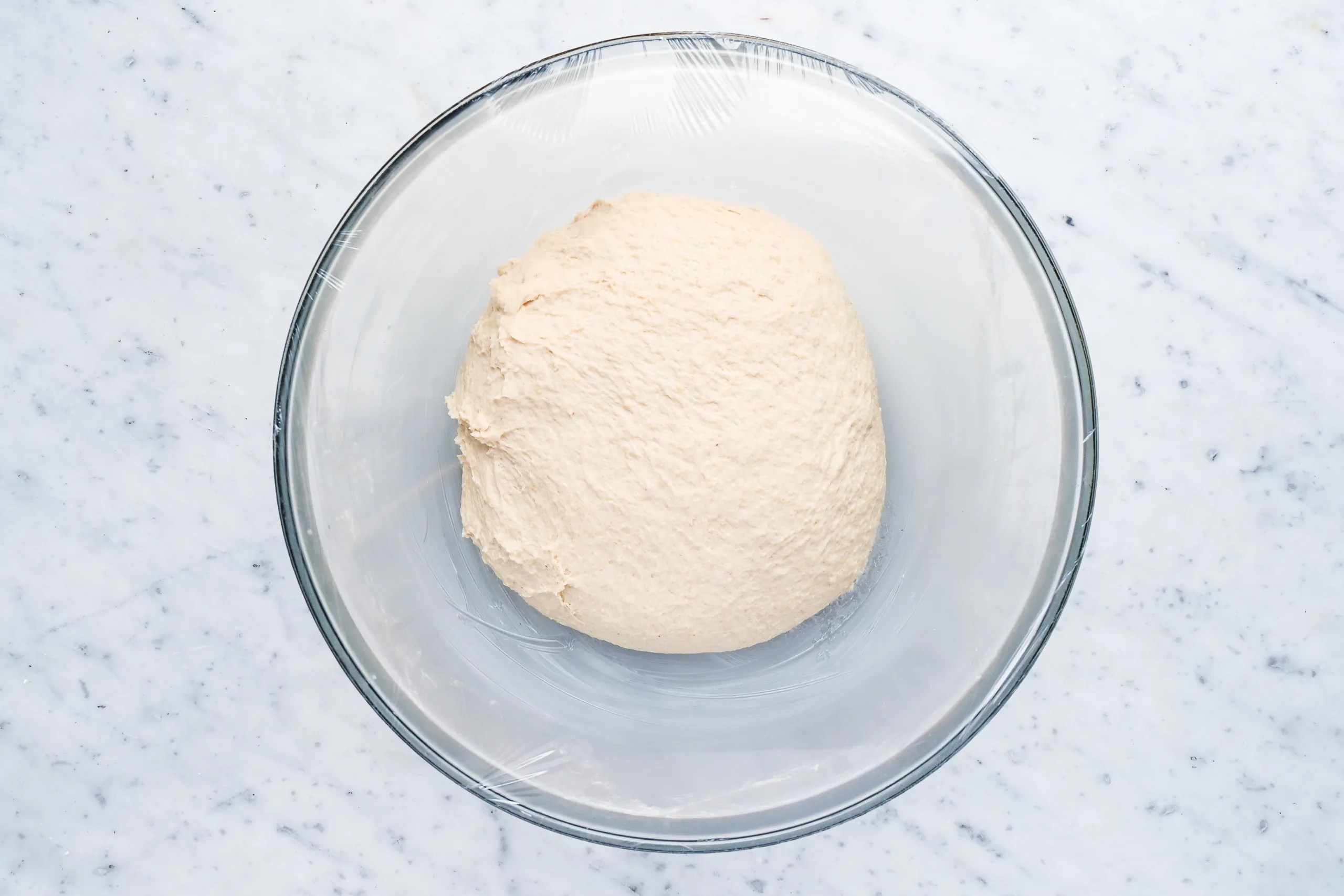 Smooth ball of sourdough discard sandwich bread dough resting in a bowl for bulk fermentation.