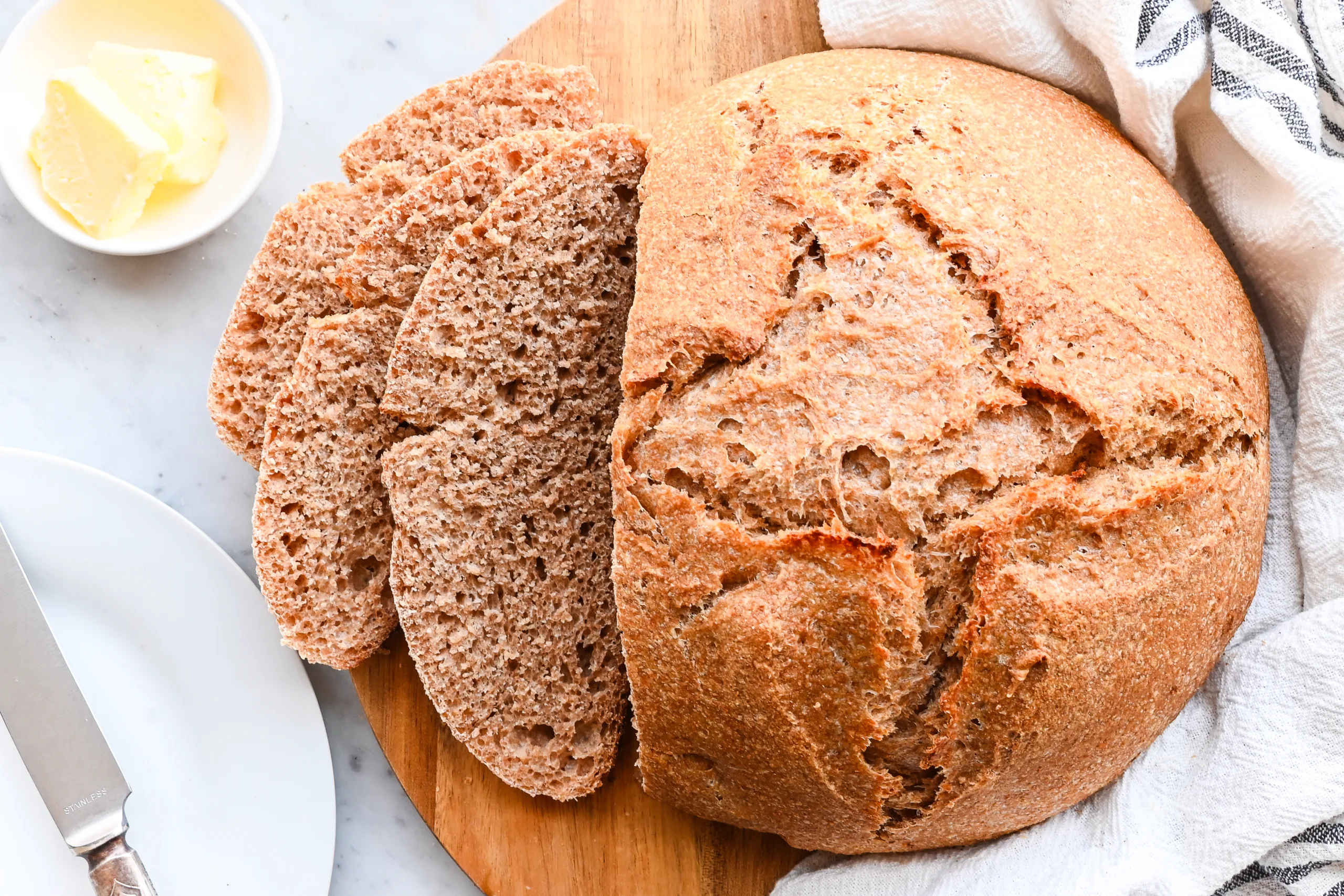 Sliced spelt sourdough bread showing the soft interior crumb next to the unsliced loaf.