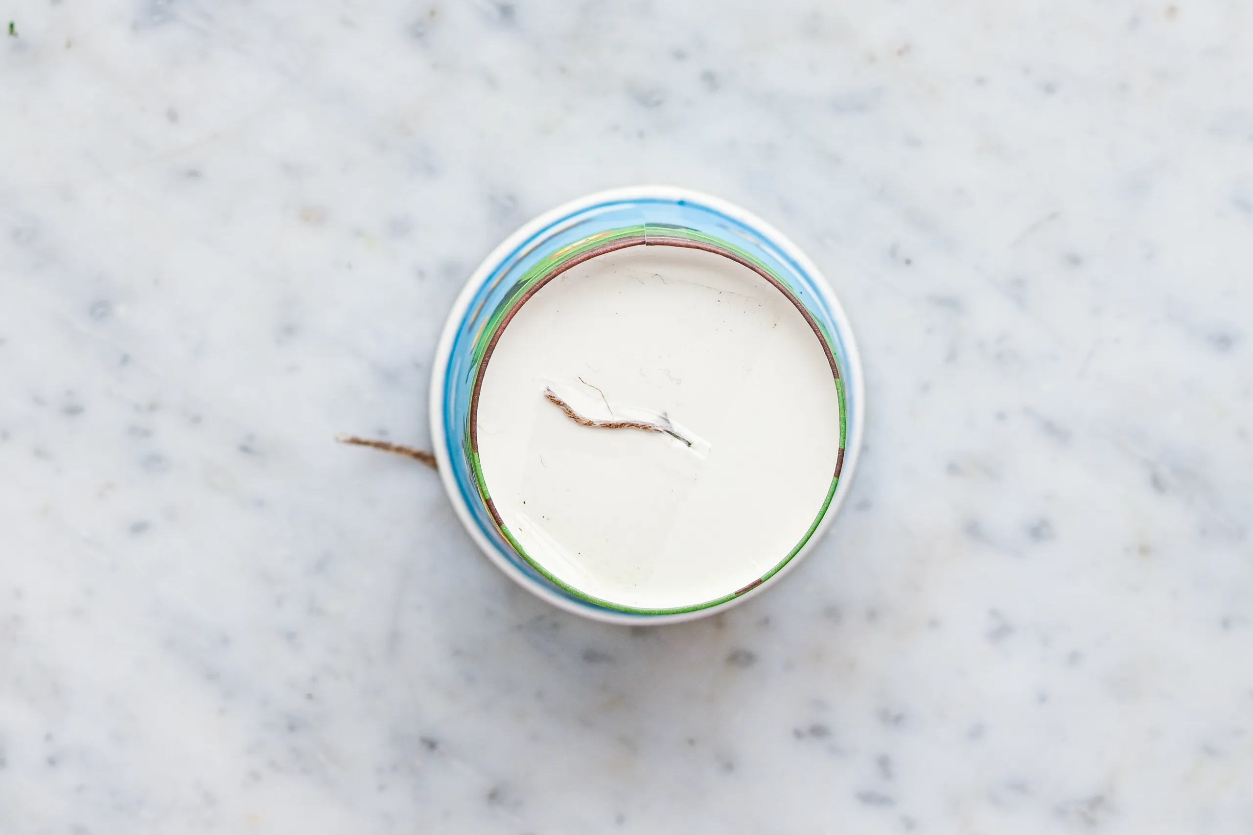 Overhead view of a paper cup with a food-safe wick centered in of the bottom being held by a piece of tape.
