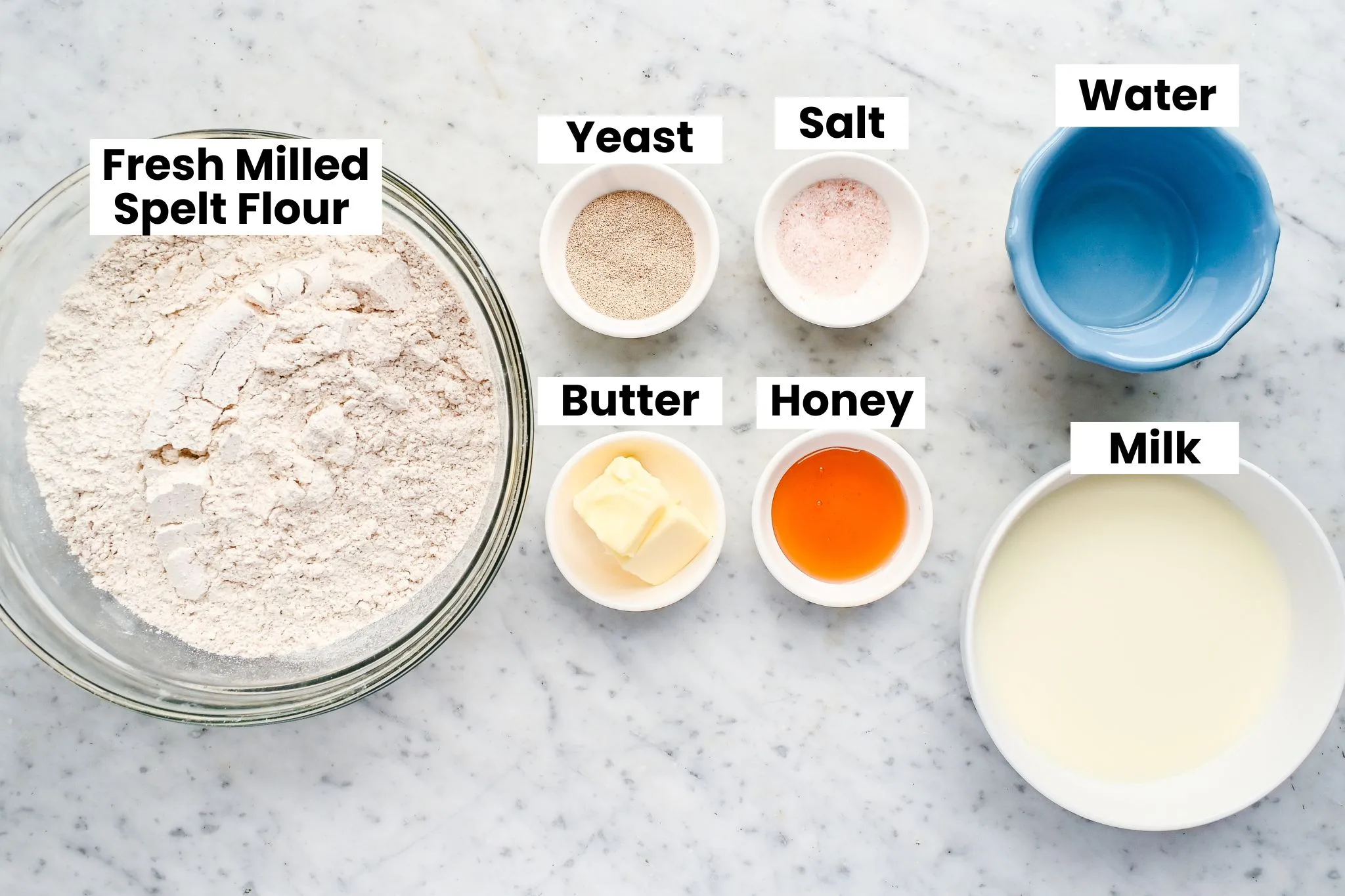 Ingredients for fresh milled whole grain spelt bread including spelt flour, yeast, salt, butter, honey, milk, and water.