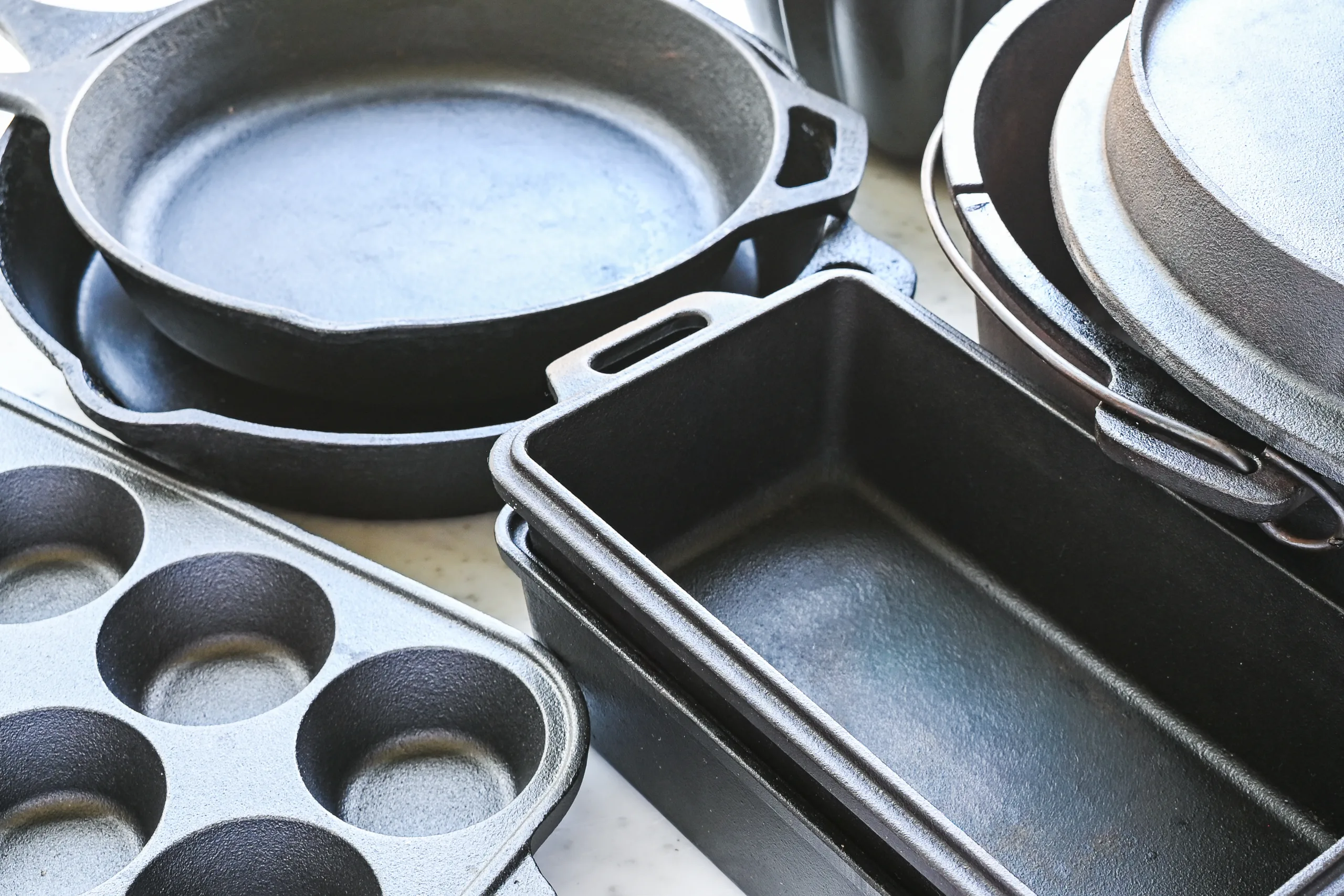Close-up of seasoned cast iron bakeware with a skillet, loaf pans, and muffin pan grouped together