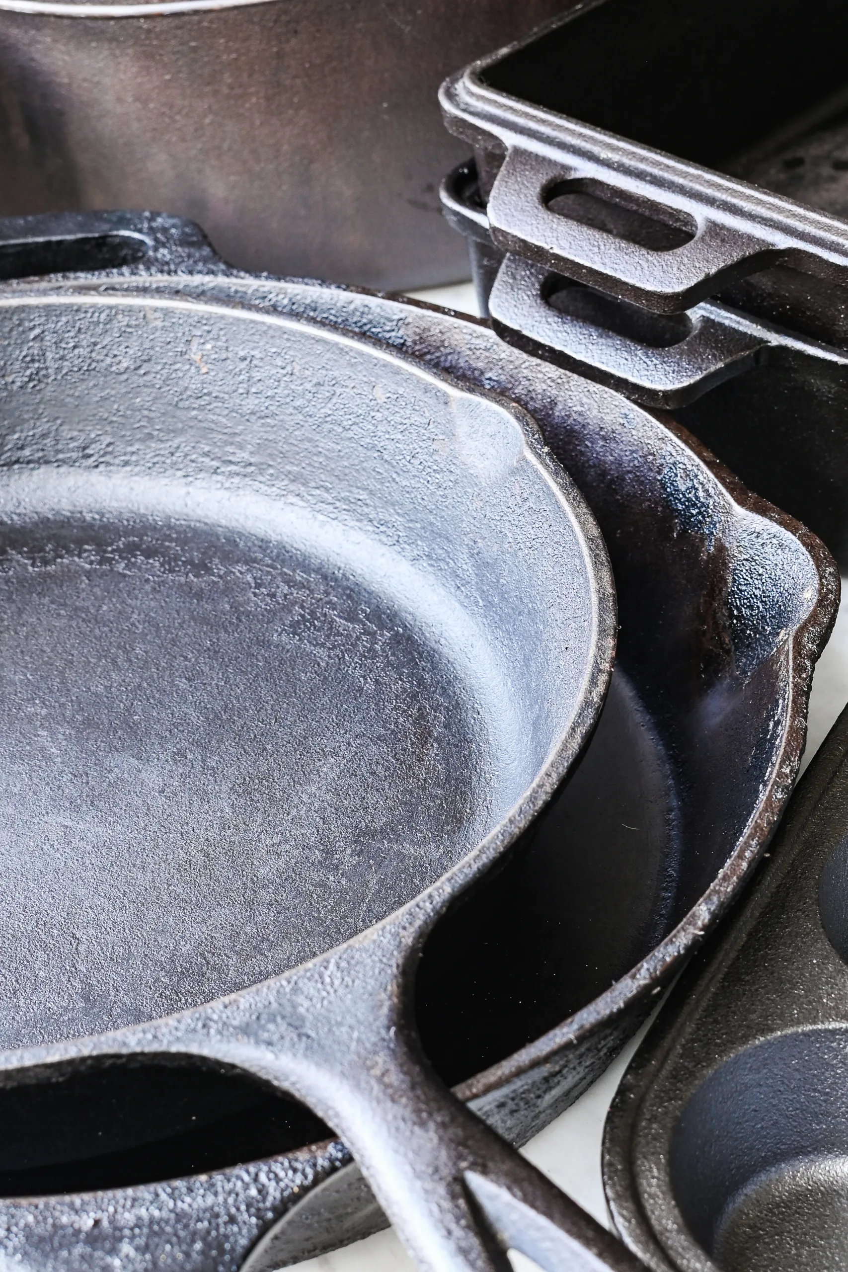 Overhead view of cast iron cookware collection with a Dutch oven, loaf pans, muffin pan, skillet, and bundt pan