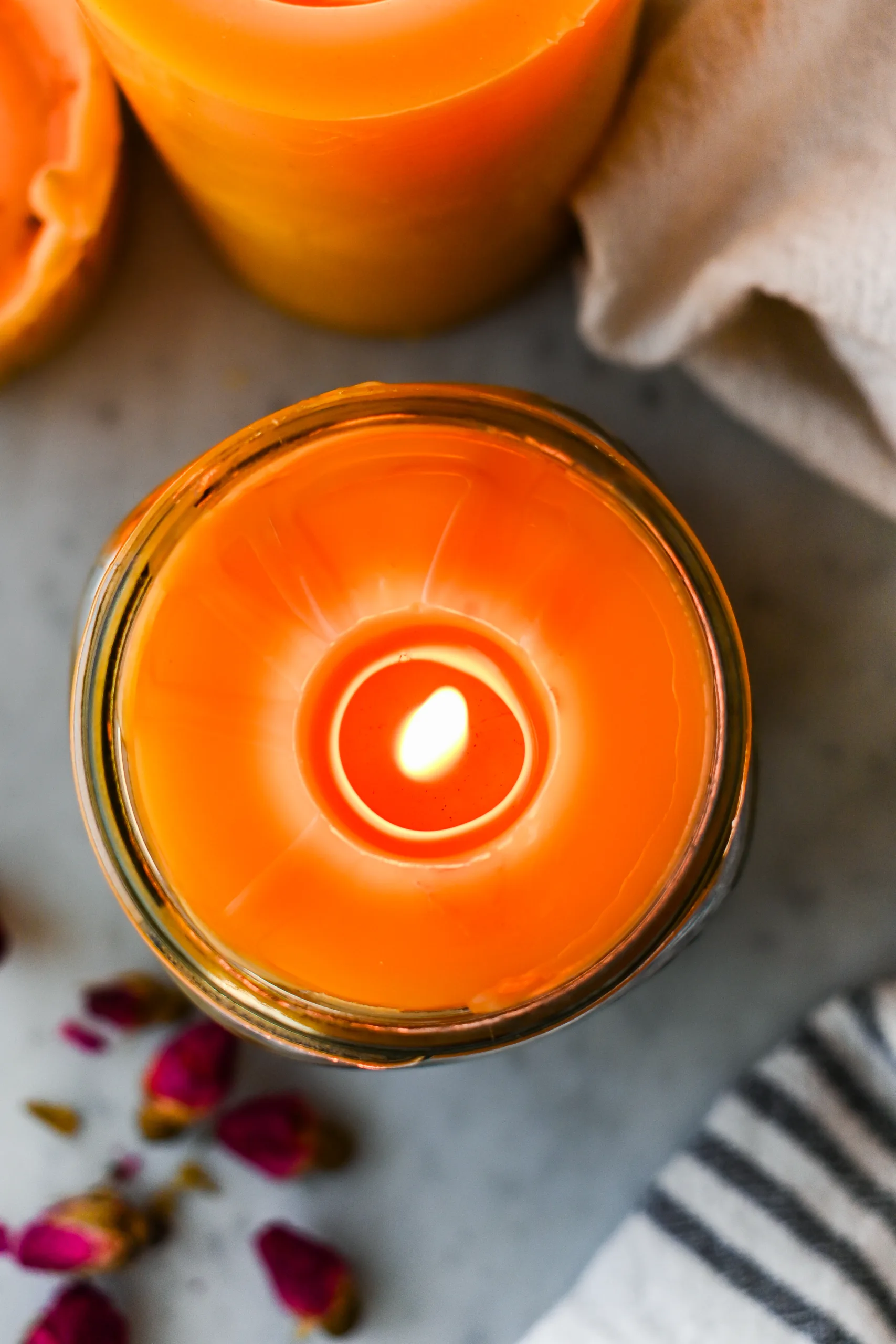 Overhead view of a burning beeswax mason jar candle with a smooth, circular melt pool