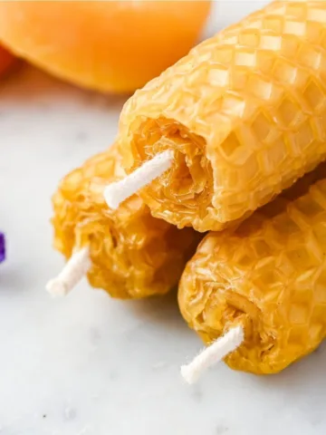 Close-up of three finished old-fashioned rolled beeswax candles with visible white cotton wicks