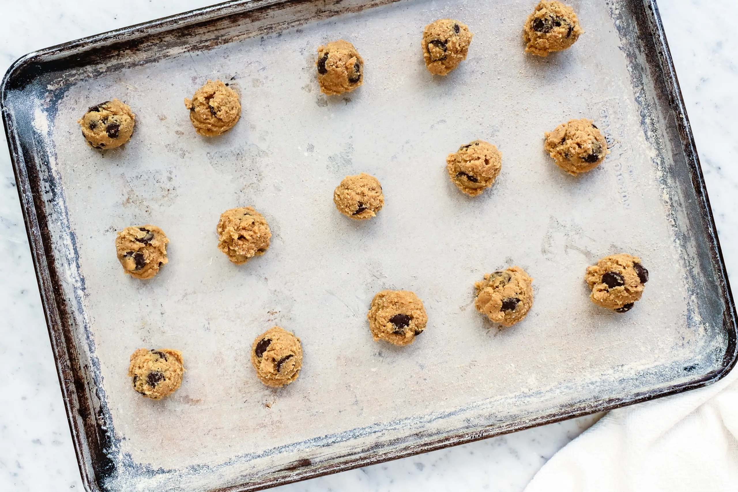 Scooped whole wheat chocolate chip cookie dough balls on a baking sheet.