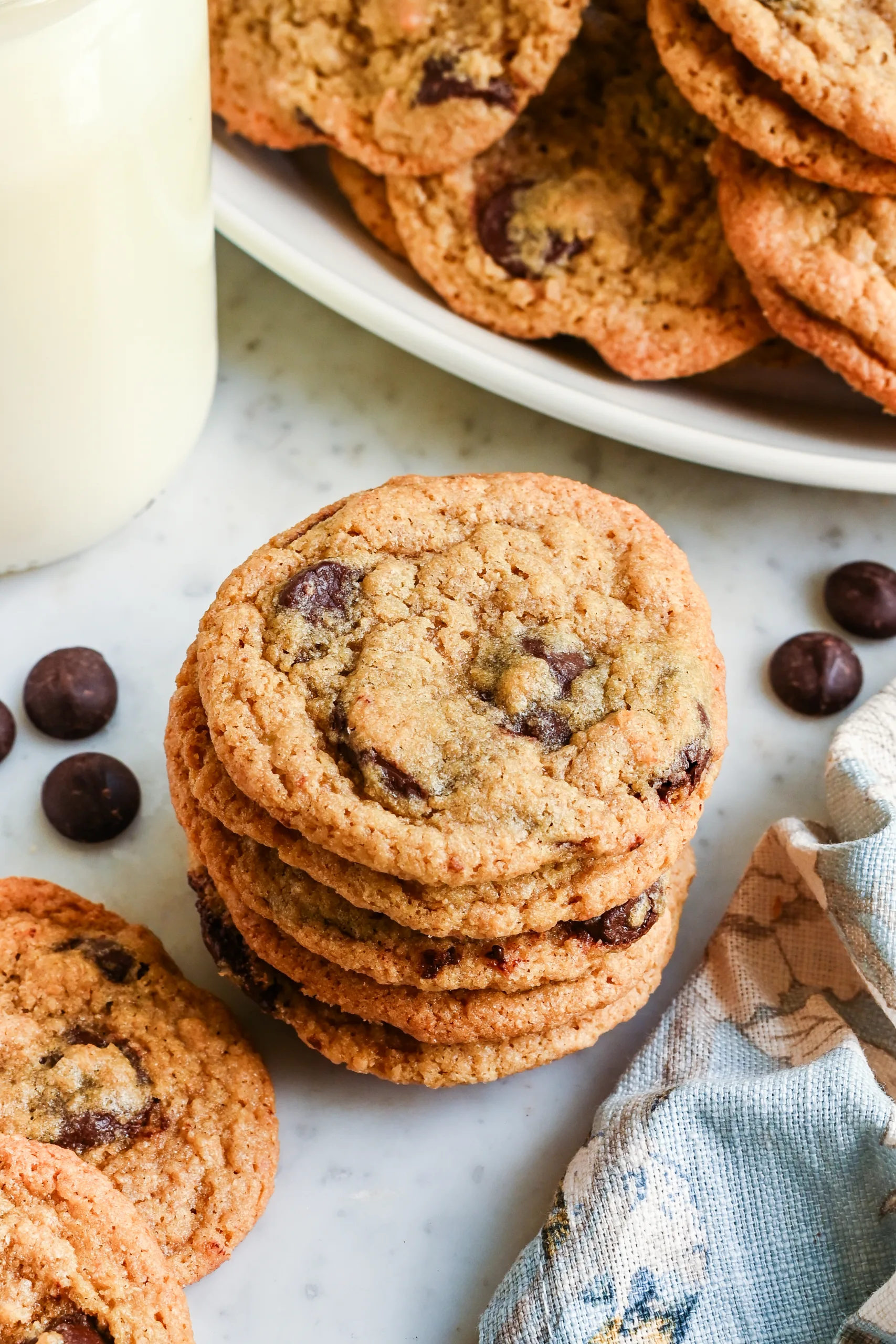 Stack of homemade whole wheat chocolate chip cookies beside a glass of milk.