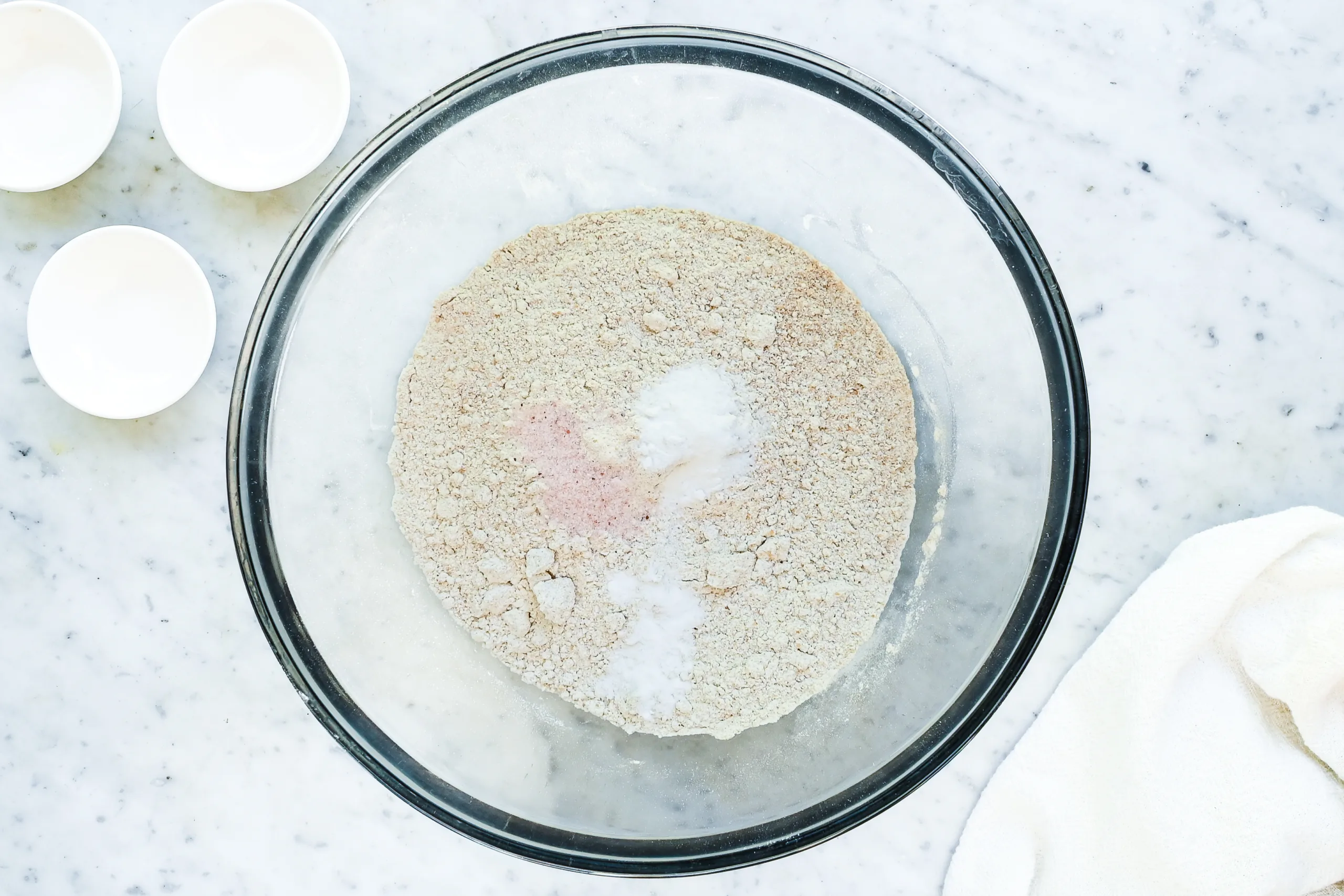 Whole wheat flour, baking soda, baking powder, and salt in a glass mixing bowl.